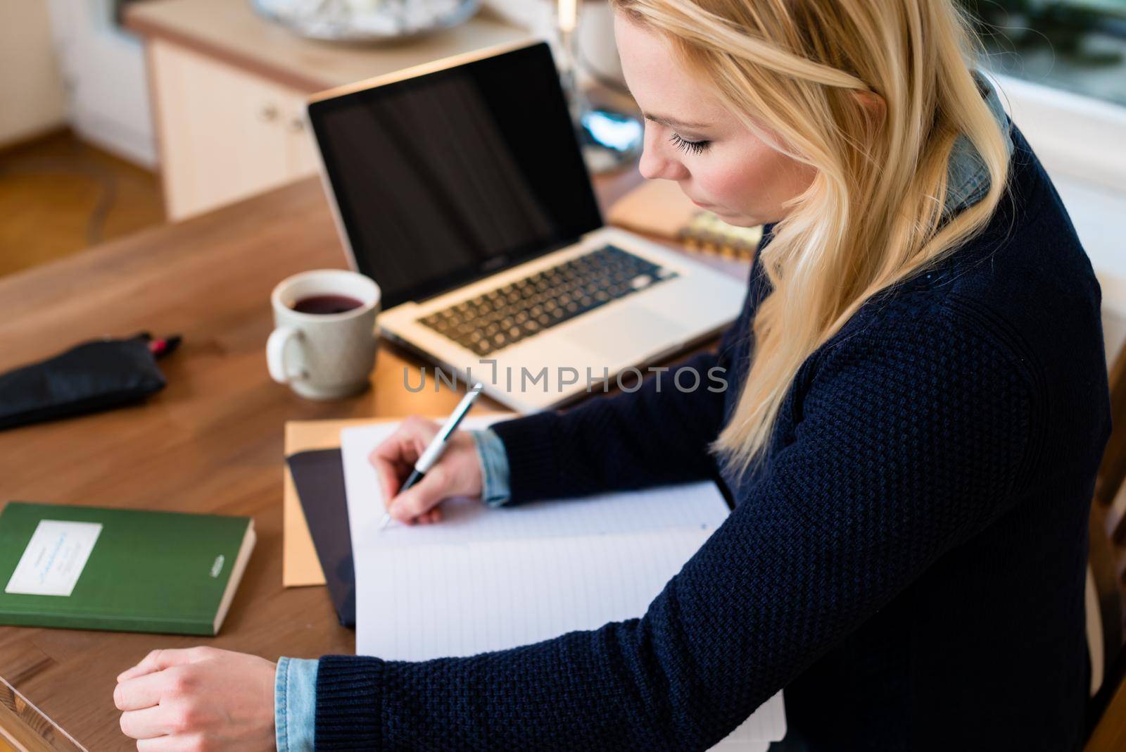Close-up of a woman at her desk writing on paper