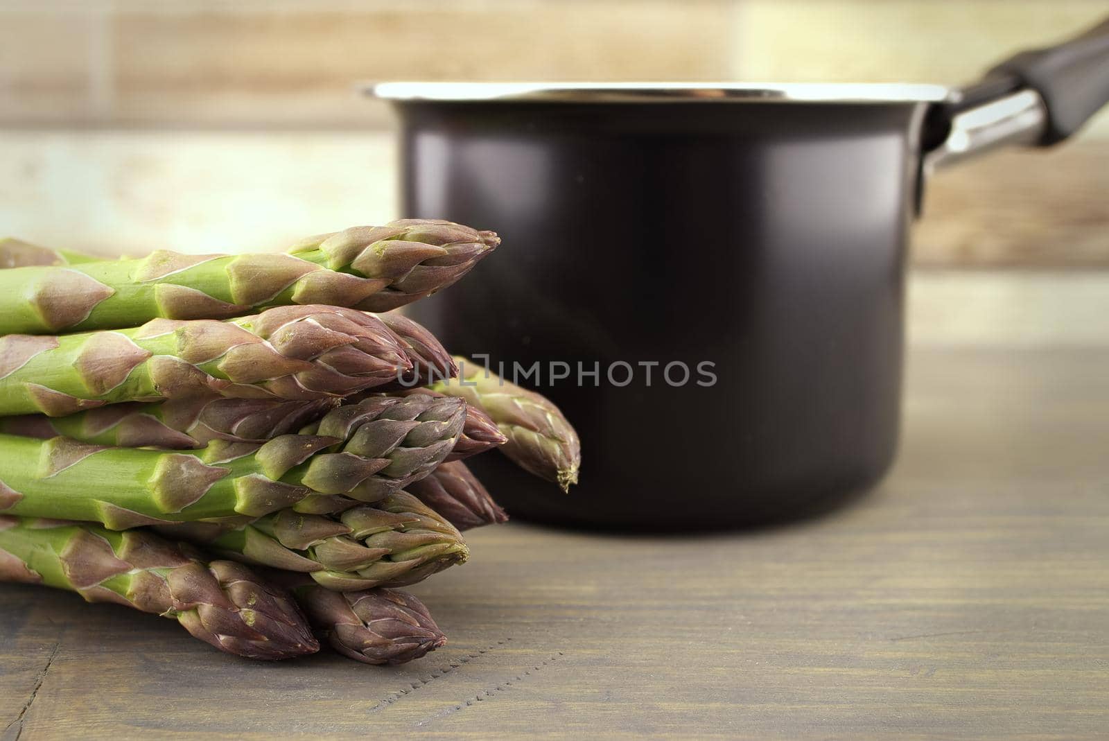 Fresh green asparagus spears near black metal pot in close up conceptual of gourmet eating in spring