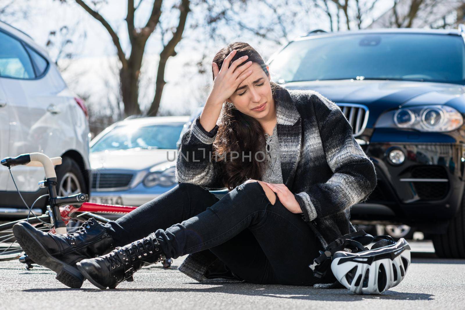 Young woman sitting on the asphalt after bicycle accident by Kzenon