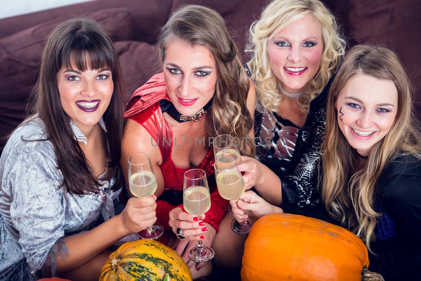 Women posing while toasting together during Halloween party by Kzenon
