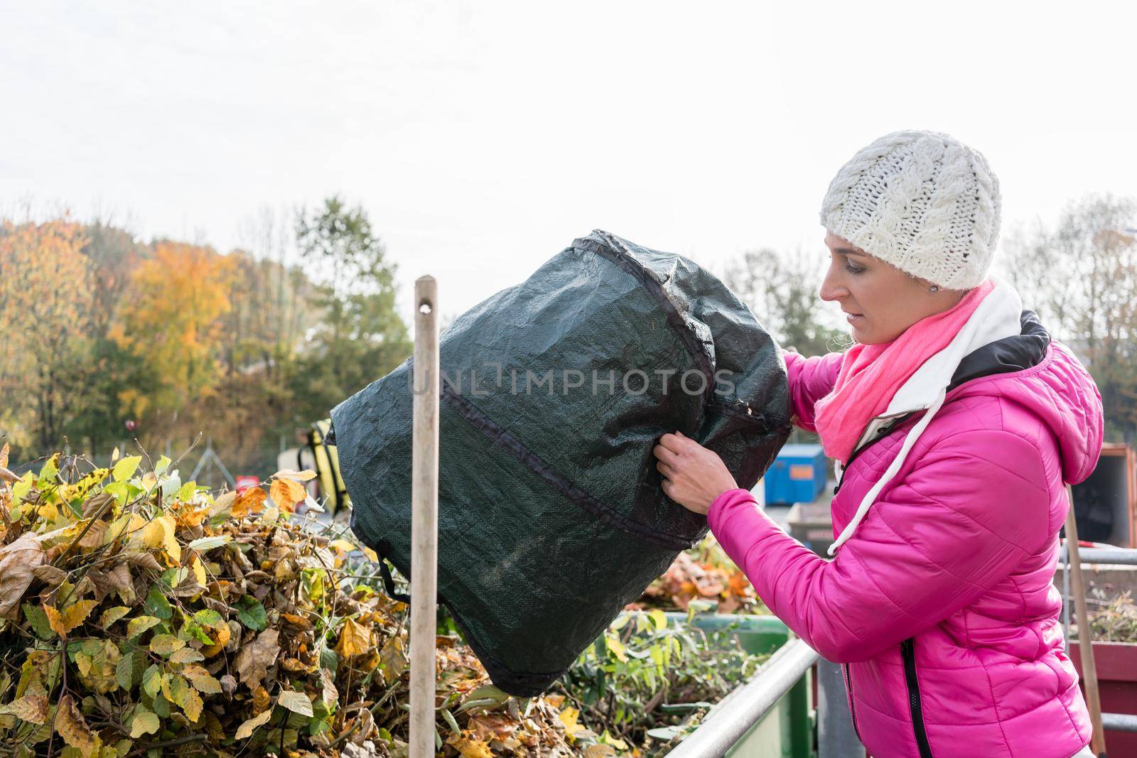 Woman giving waste green in container at recycling center by Kzenon