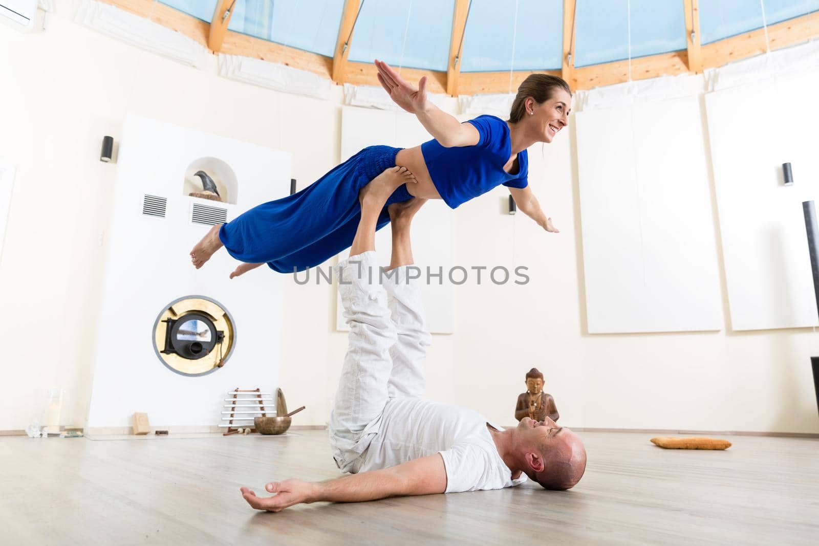 Happy man and woman performing acroyoga in gym