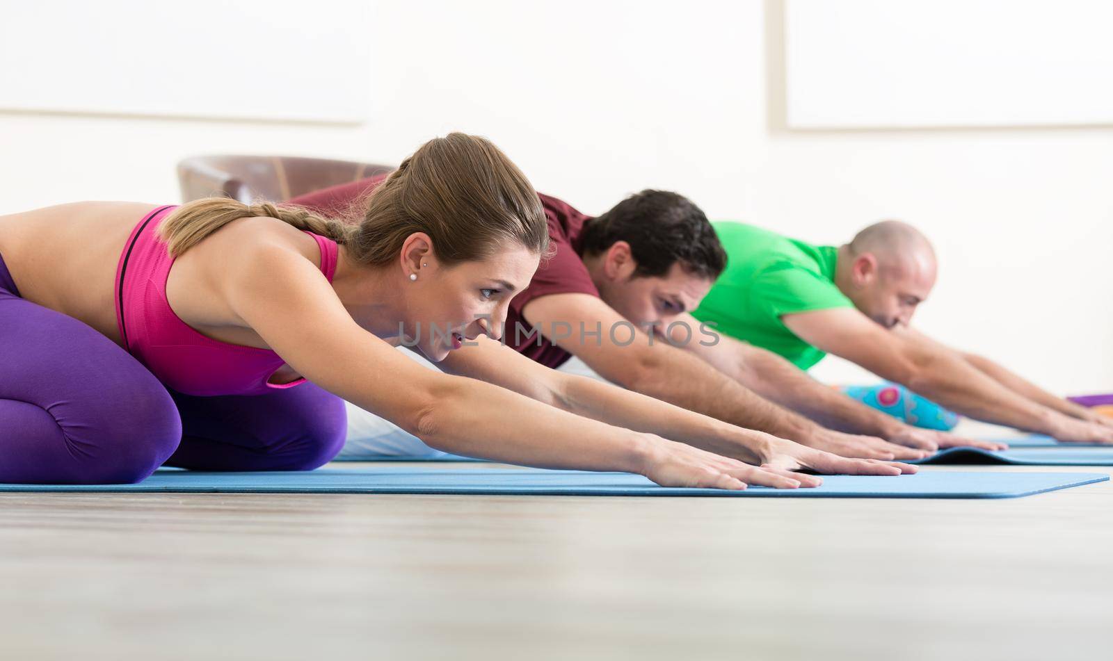 Group of sporty people practicing yoga lesson with instructor