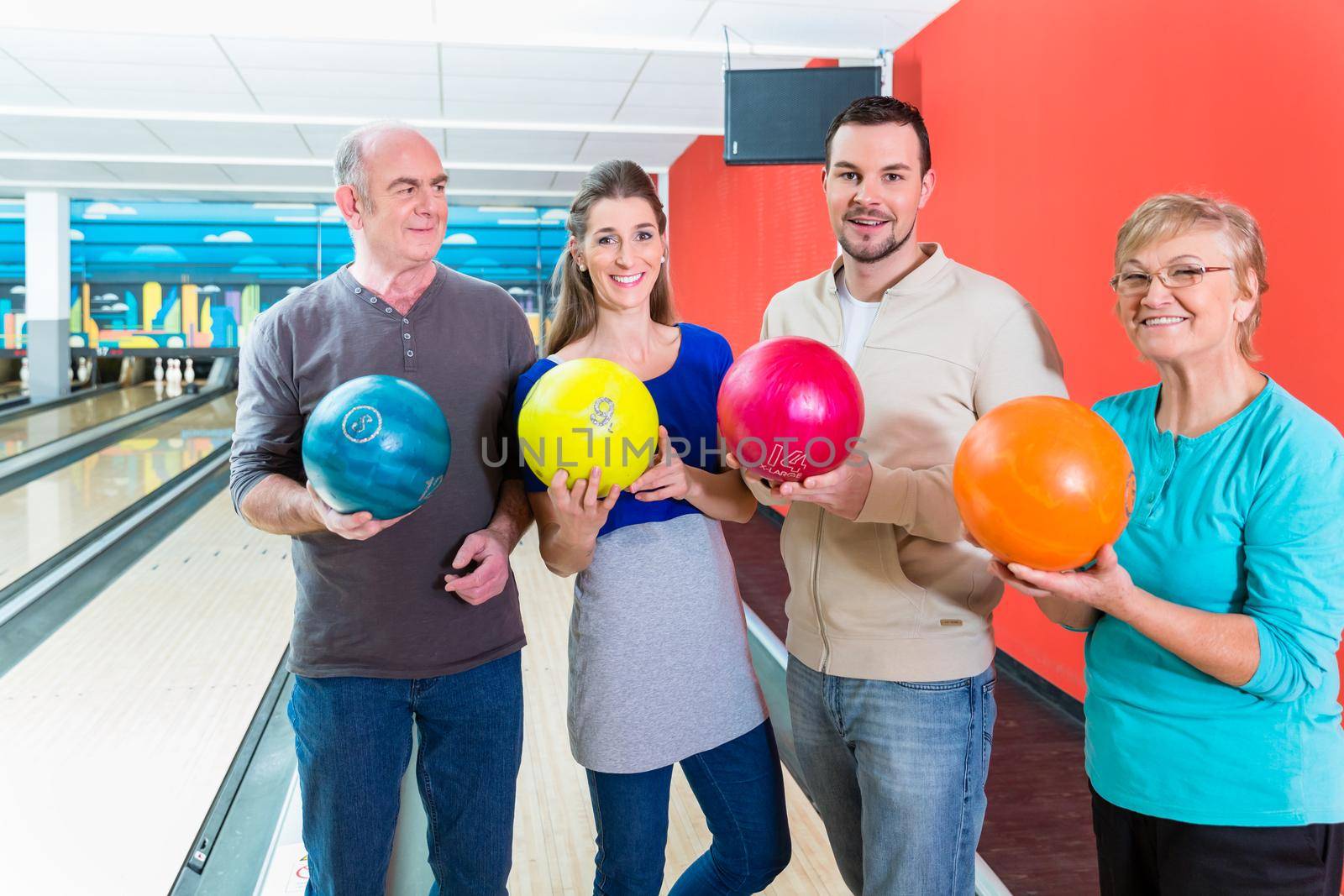 Smiling family holding multi colored bowling ball