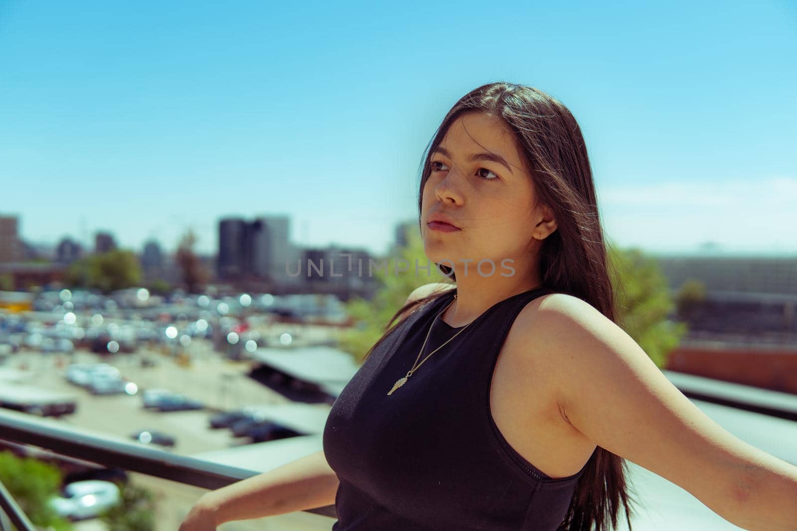 Young girl leaning on a railing with the city of madrid in the background.