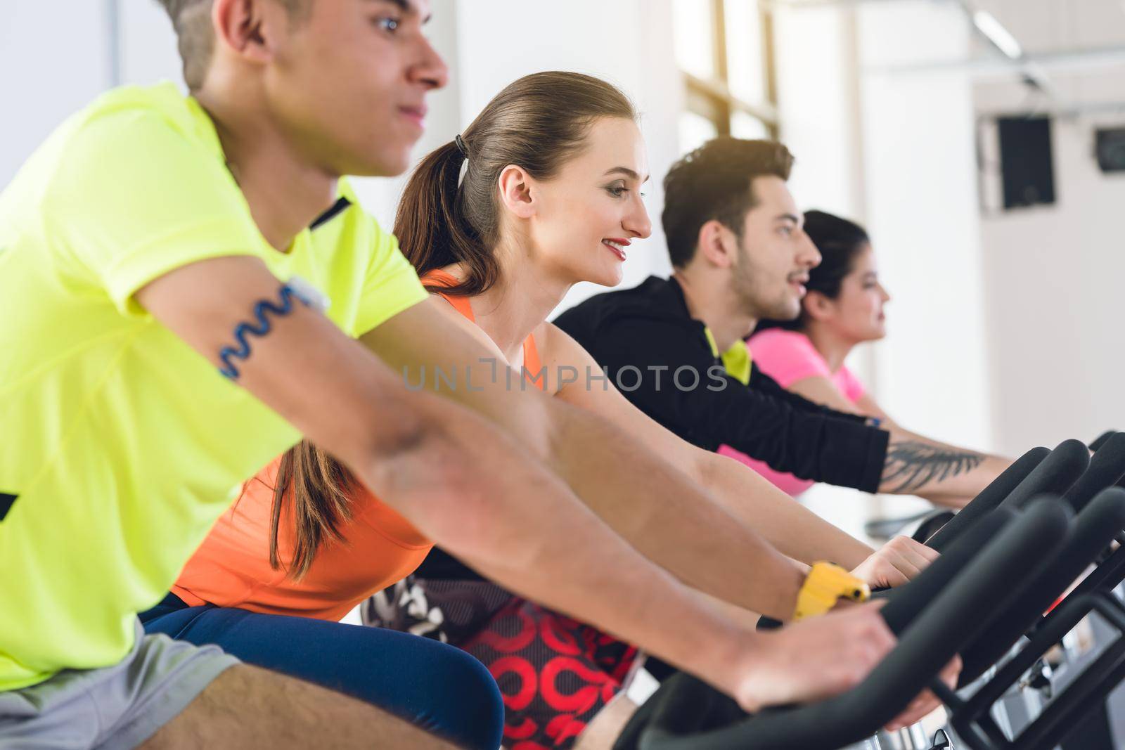 Group friends cycling in a row at gym