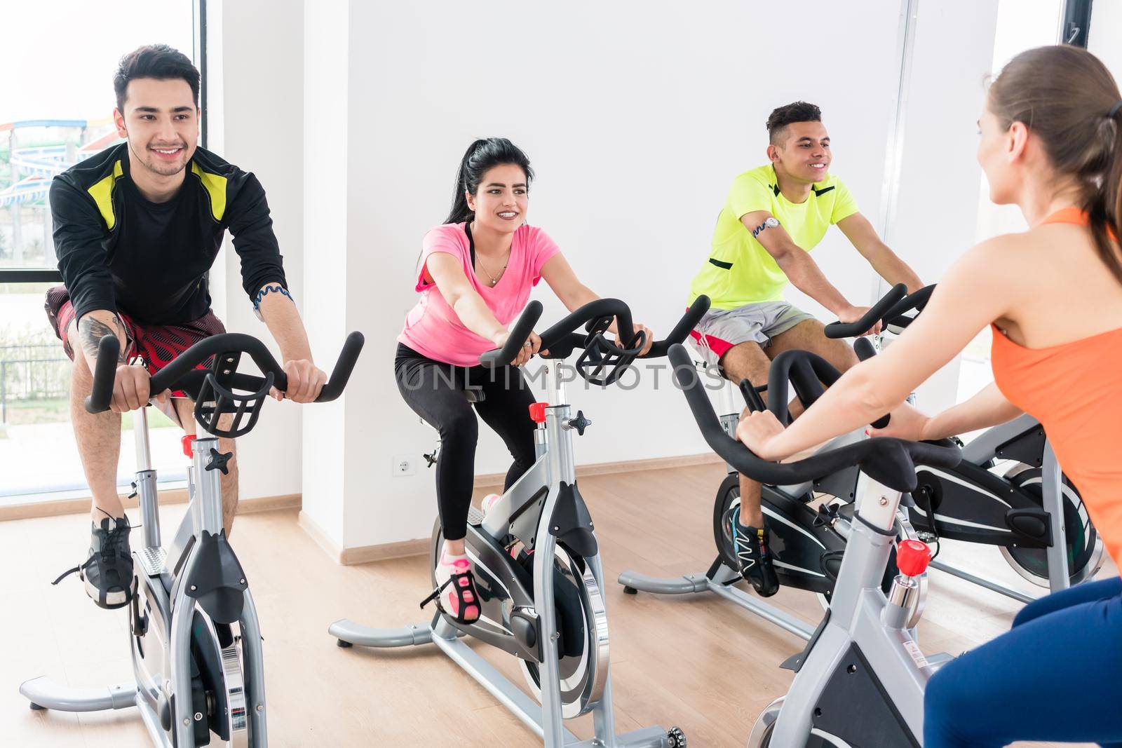 Group of young people cycling at gym