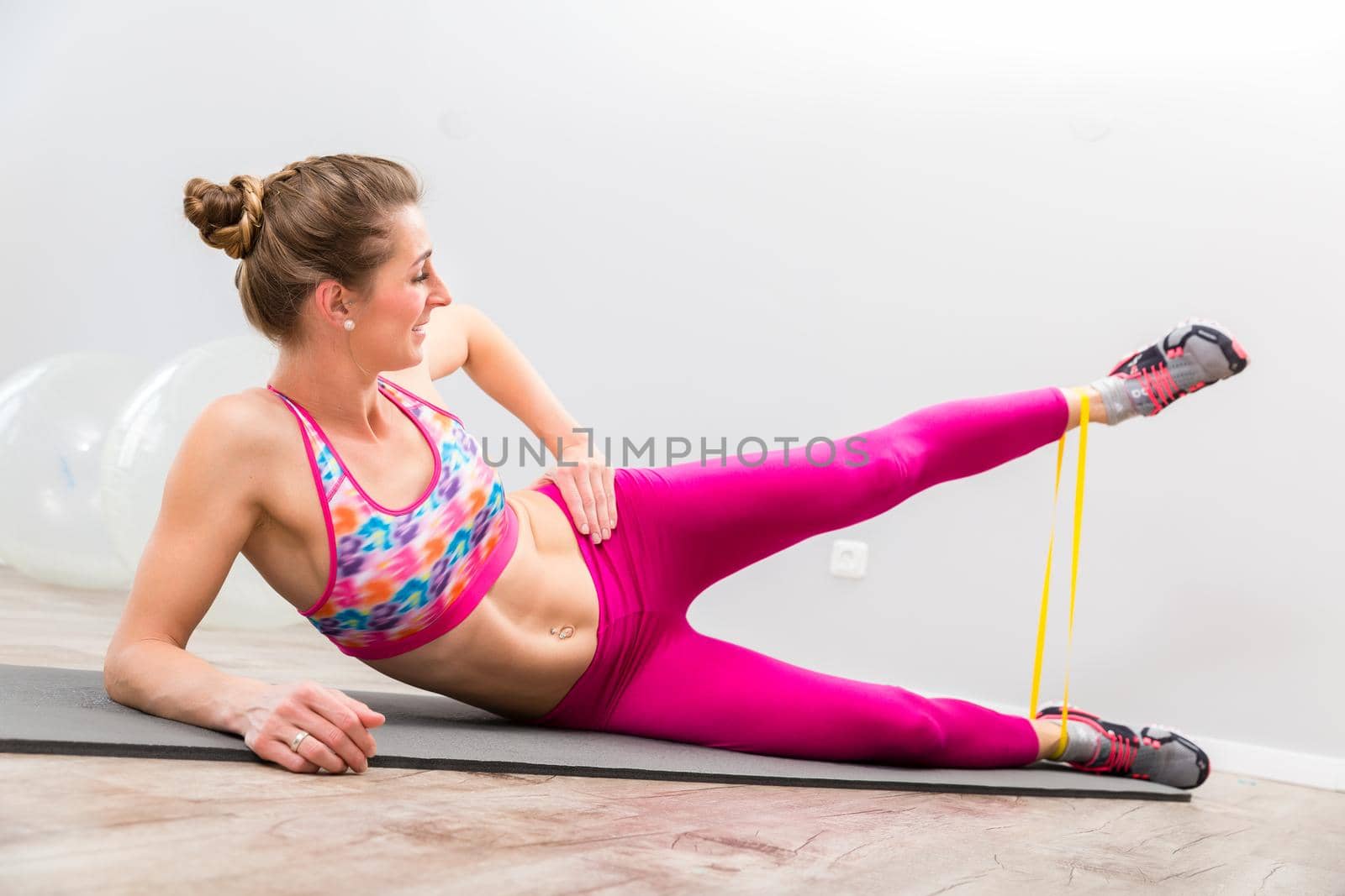 Healthy young woman doing exercise with yellow resistance band in the gym