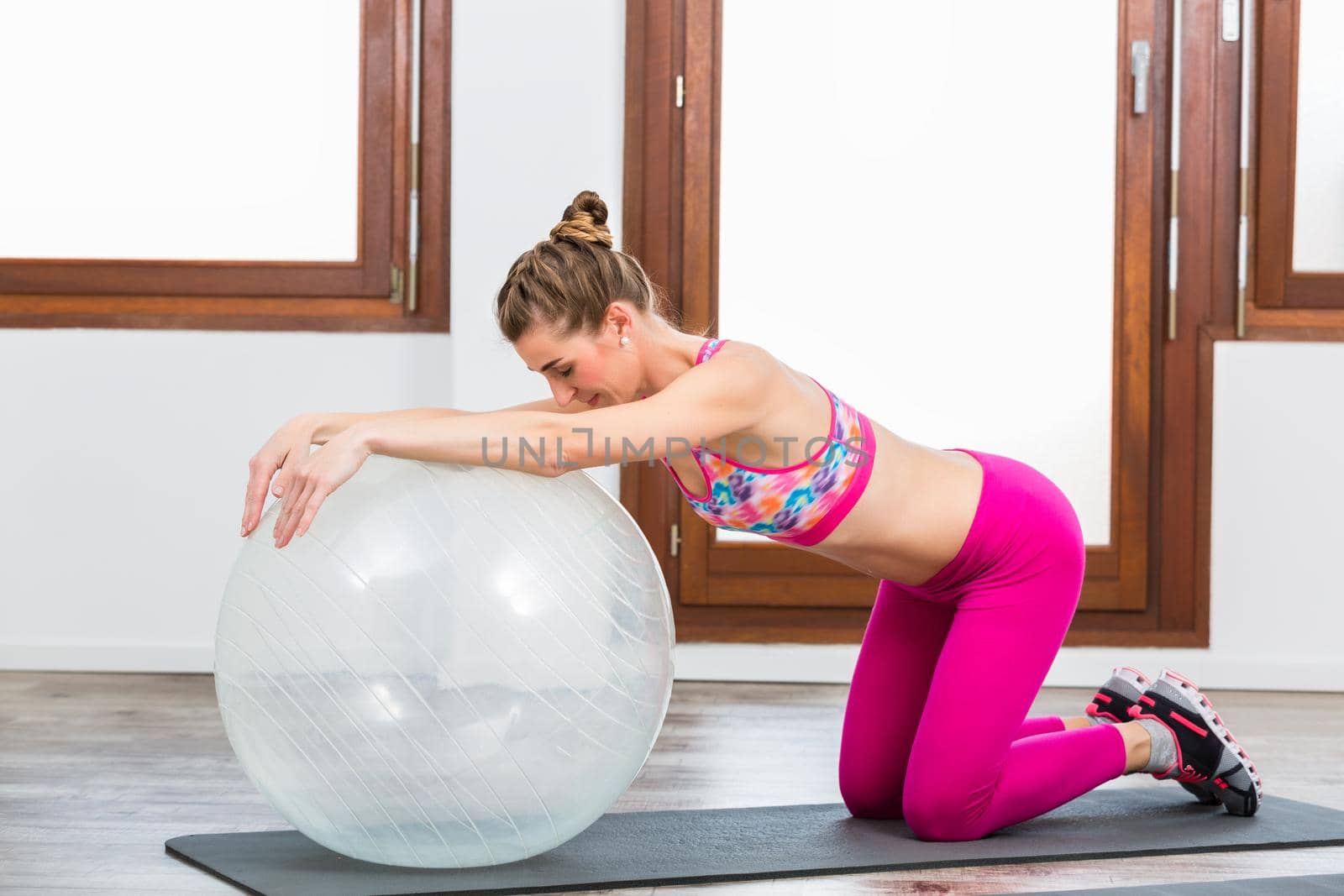 Side view of woman doing exercise on pilates ball on exercise mat in gym