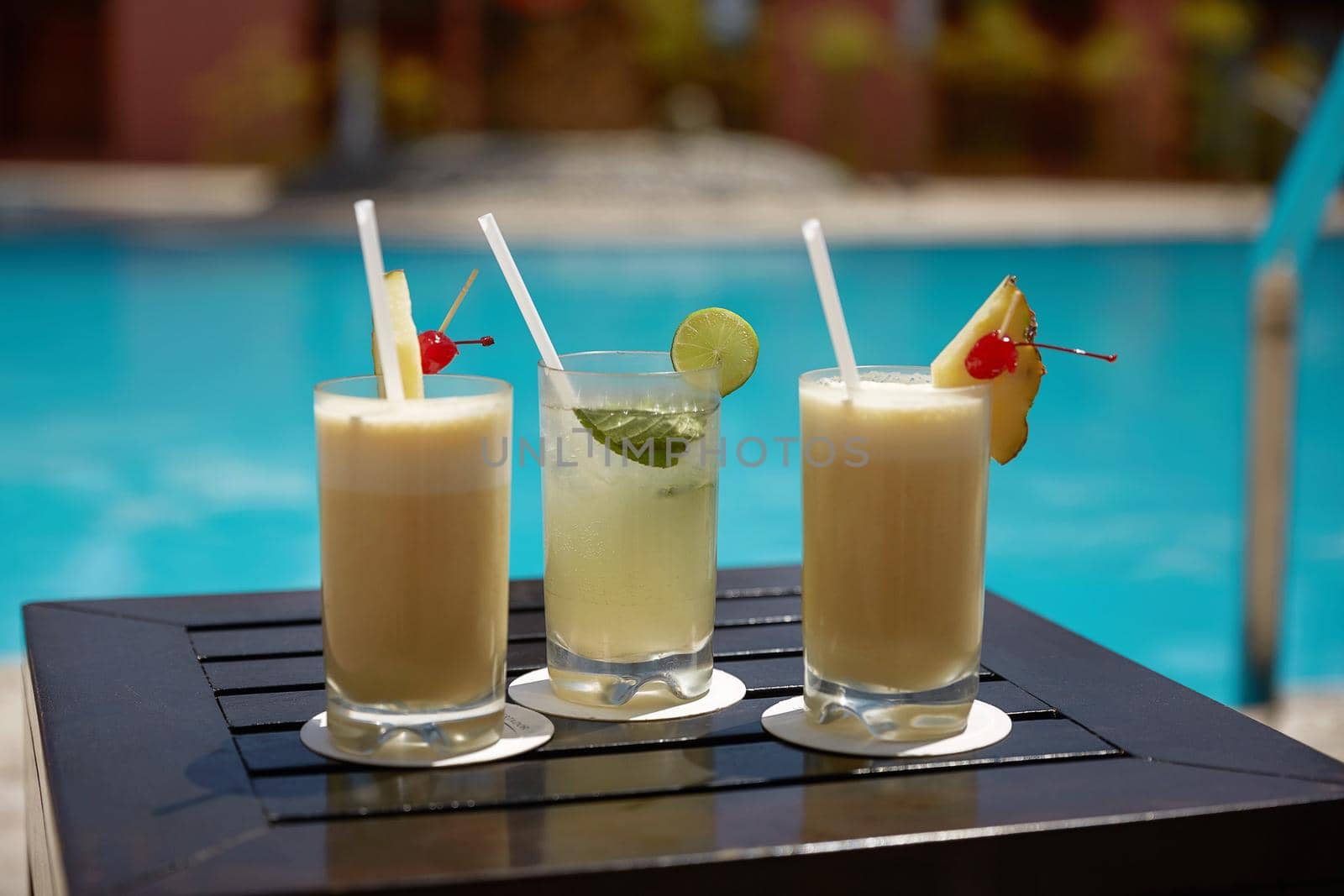 Cocktails of Mojito and  Pina Colada on Wooden Table Near the Swimming Pool During Summer.