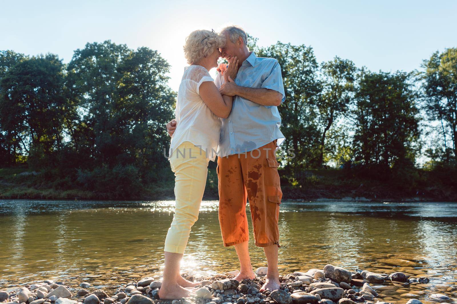 Low-angle side view portrait of a romantic senior couple in love enjoying a healthy and active lifestyle outdoors in summer