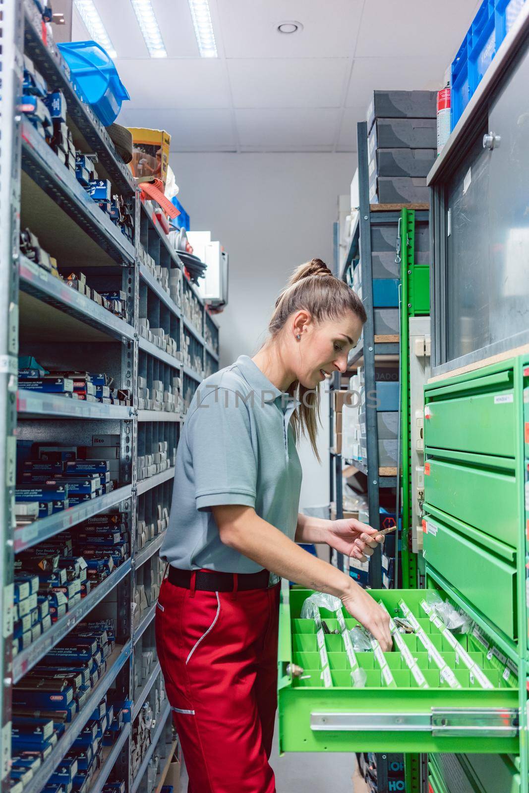Woman in storeroom of key maker store choosing parts