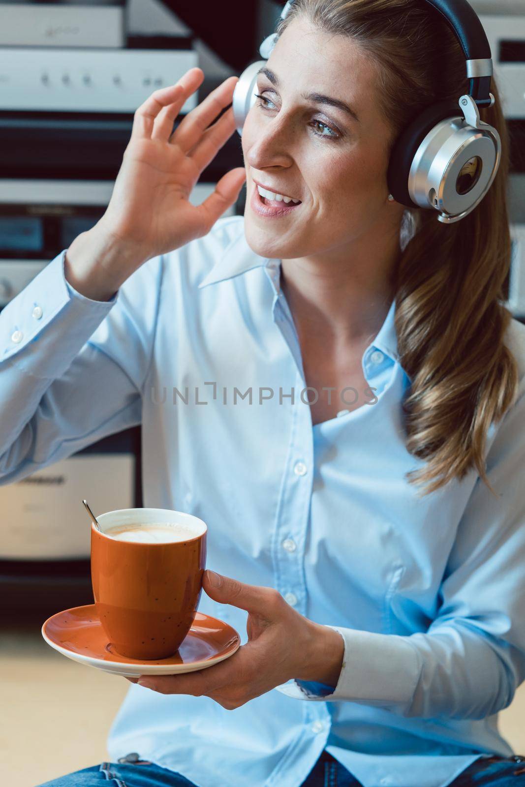 Woman drinking coffee and listening to music sitting on the floor of her home