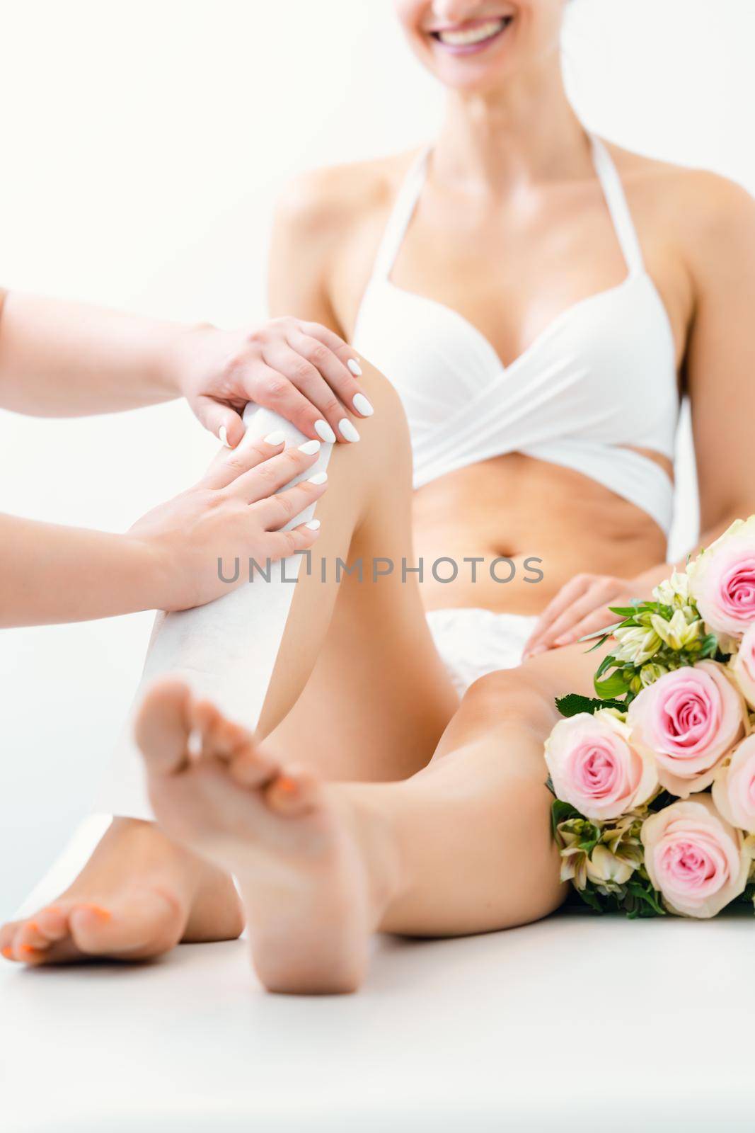 Hair removal using wax strips on legs of woman in beauty parlor