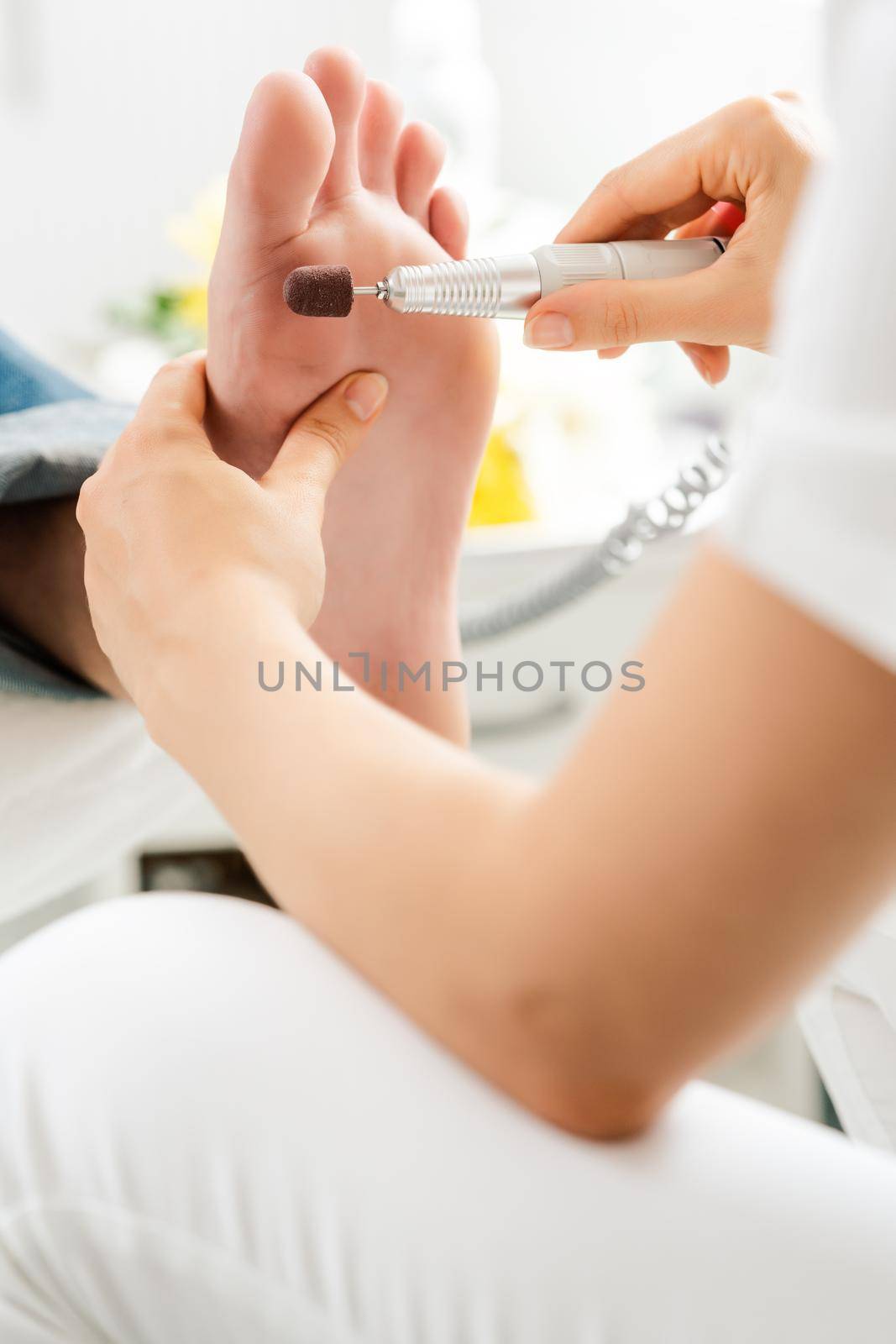 Man during medical podiatry session, podiatrist is removing hard skin