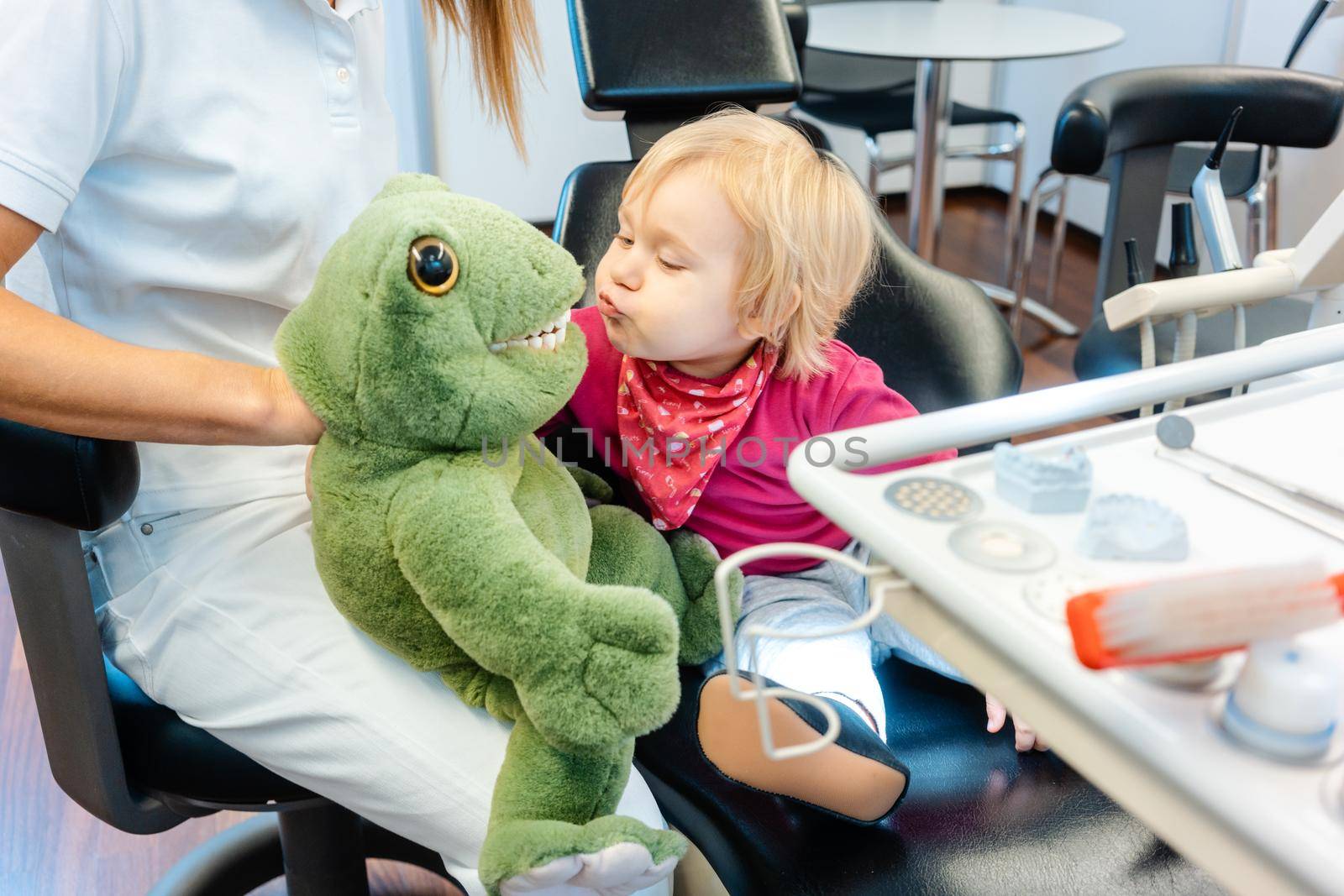 Child at the dentist brushing teeth of a plush toy learning how to do it