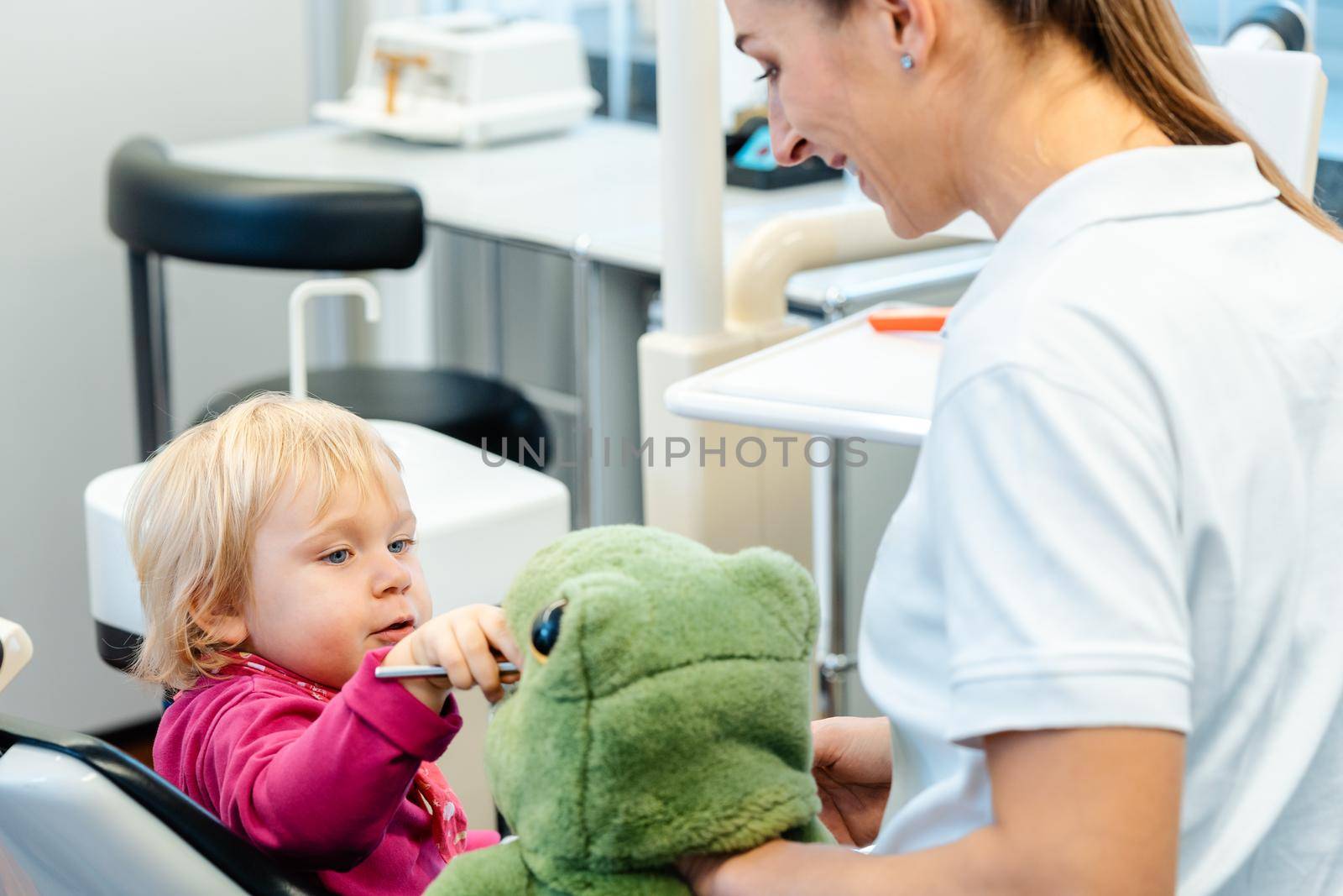 Little child in dentists surgery learning how to brush teeth by Kzenon