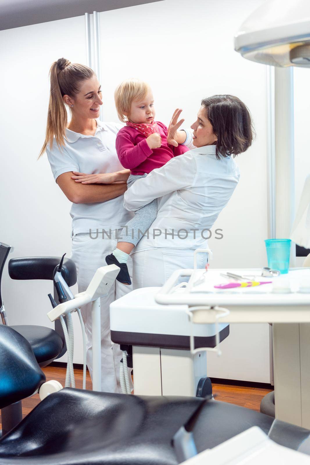 Playful dentist and her assistant with child in the office