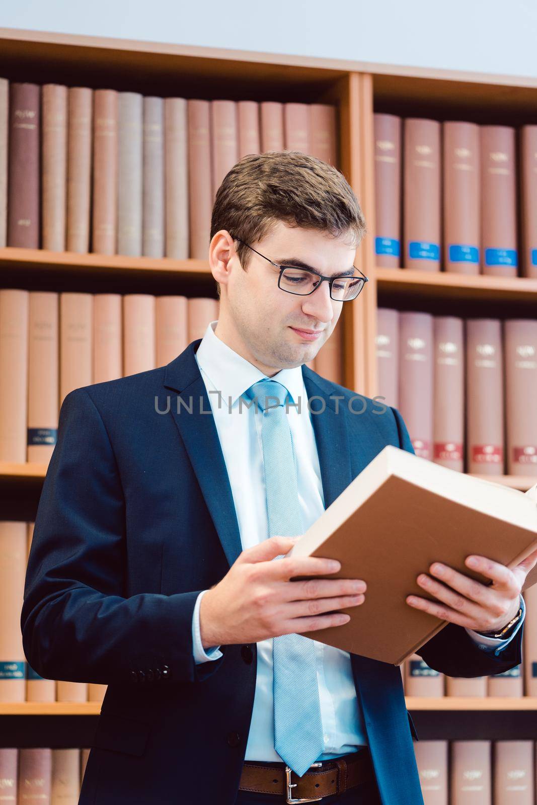Lawyer in his office reading precedents in thick books by Kzenon