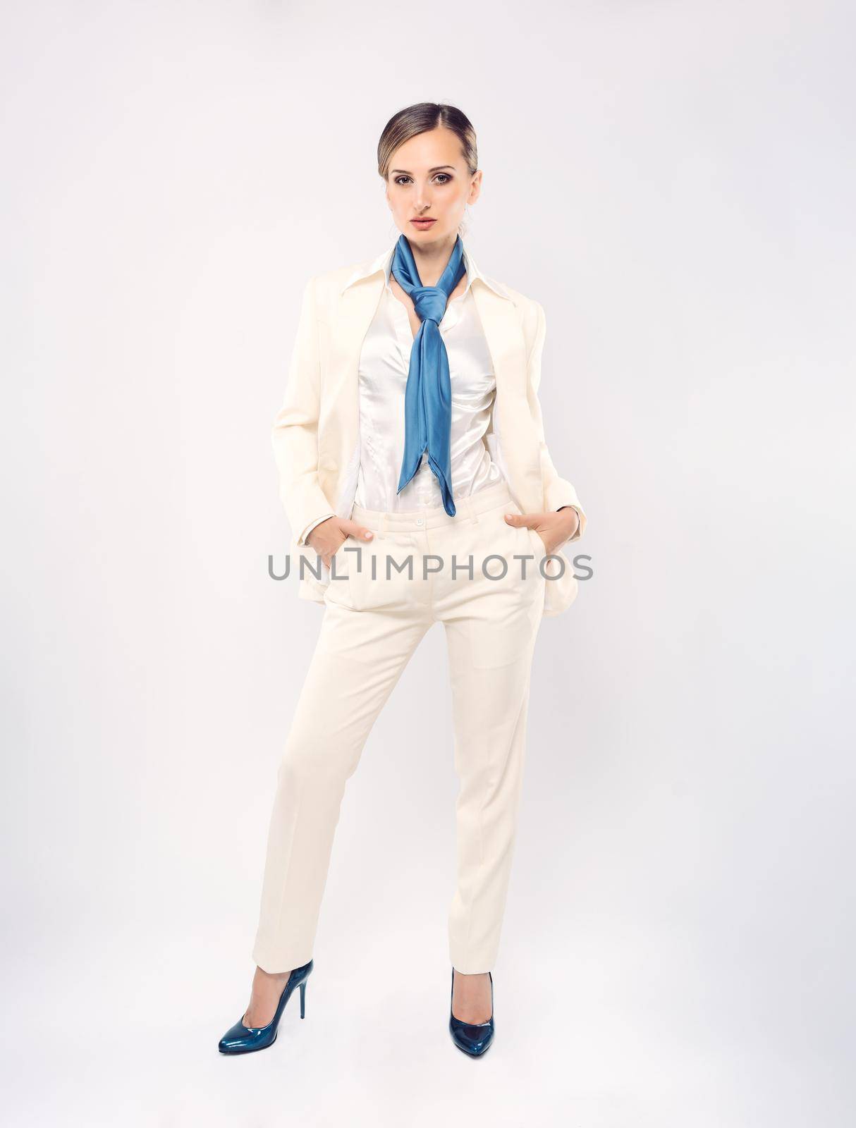 Fashionable businesswoman wearing white suit and blue scarf, studio shot