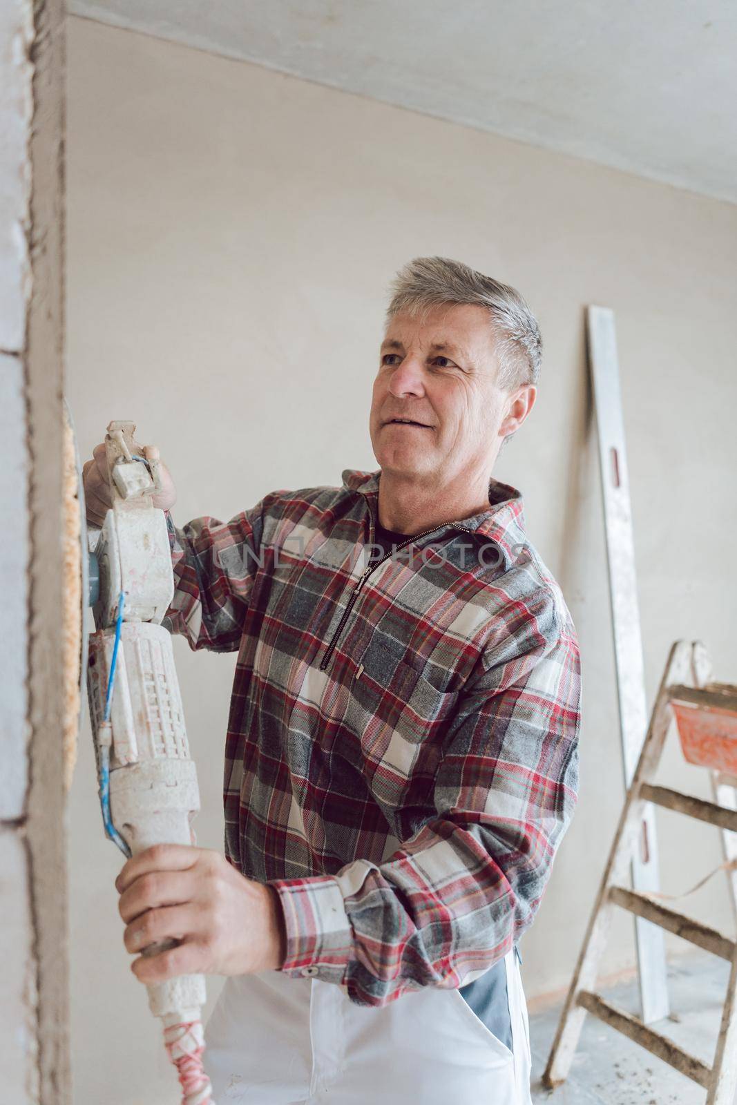 Plasterer smoothing interior wall of new homes with machine