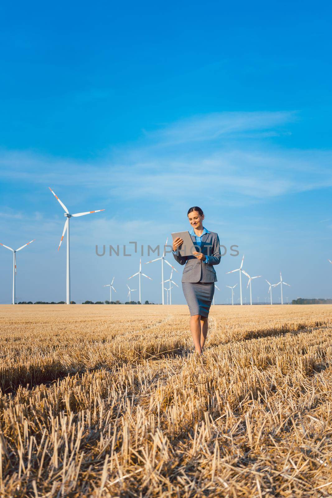 Women putting money into an ethical Investment of wind turbines, standing with her computer on a field