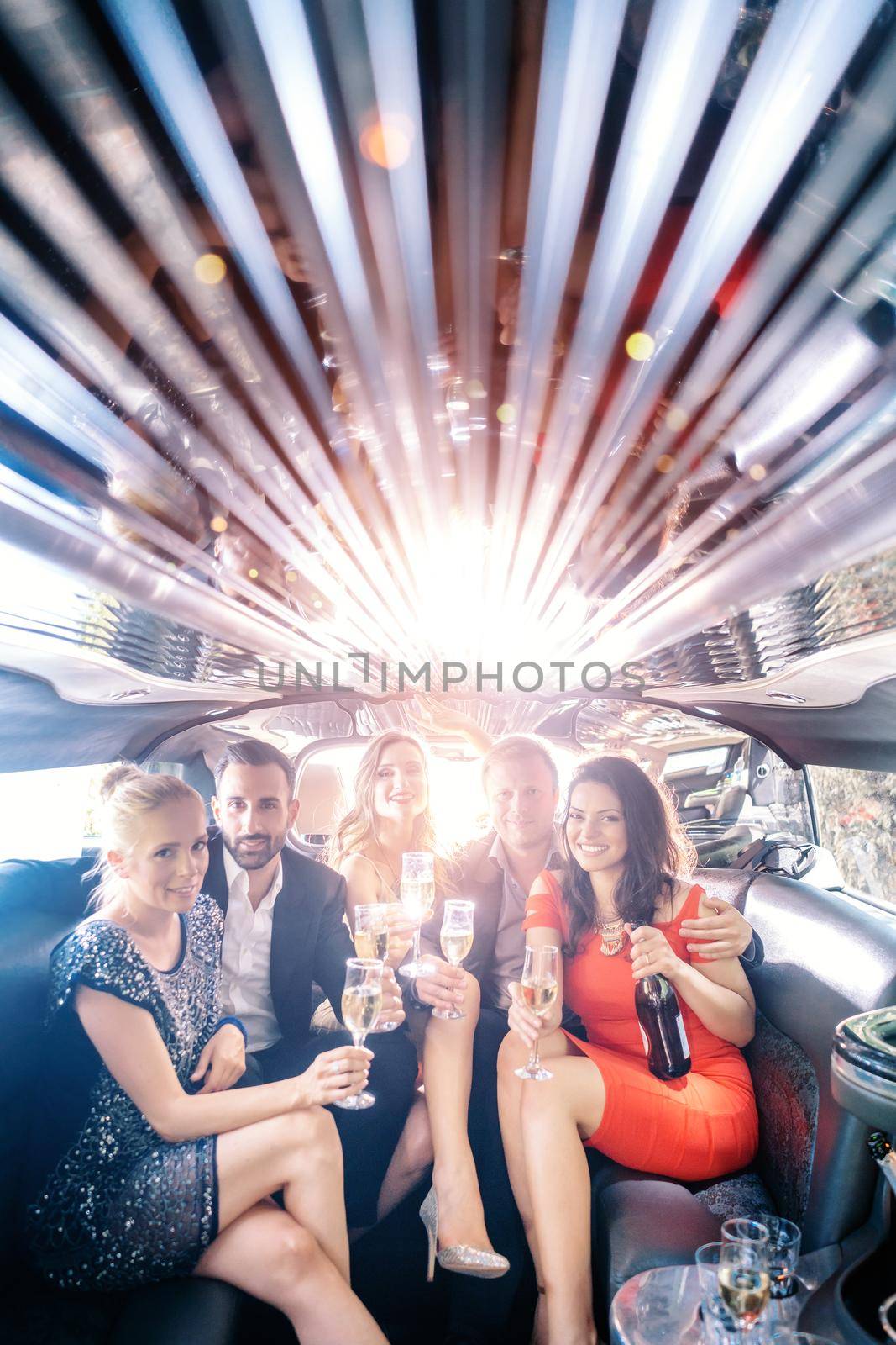 Celebration in a limo, woman and men drinking champagne by Kzenon