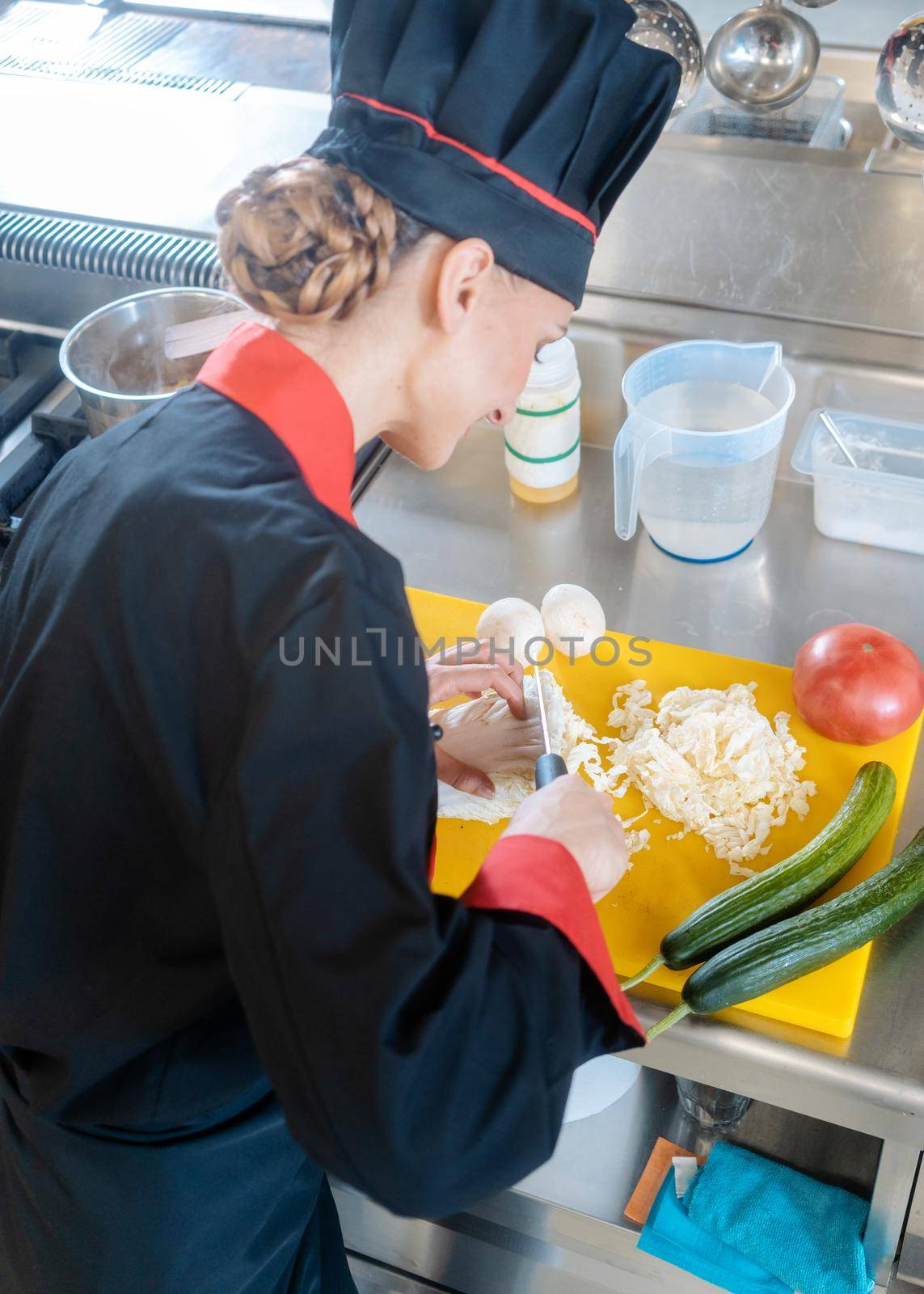 A female chef slicing cauliflower on a yellow chopping board in pieces for a meal