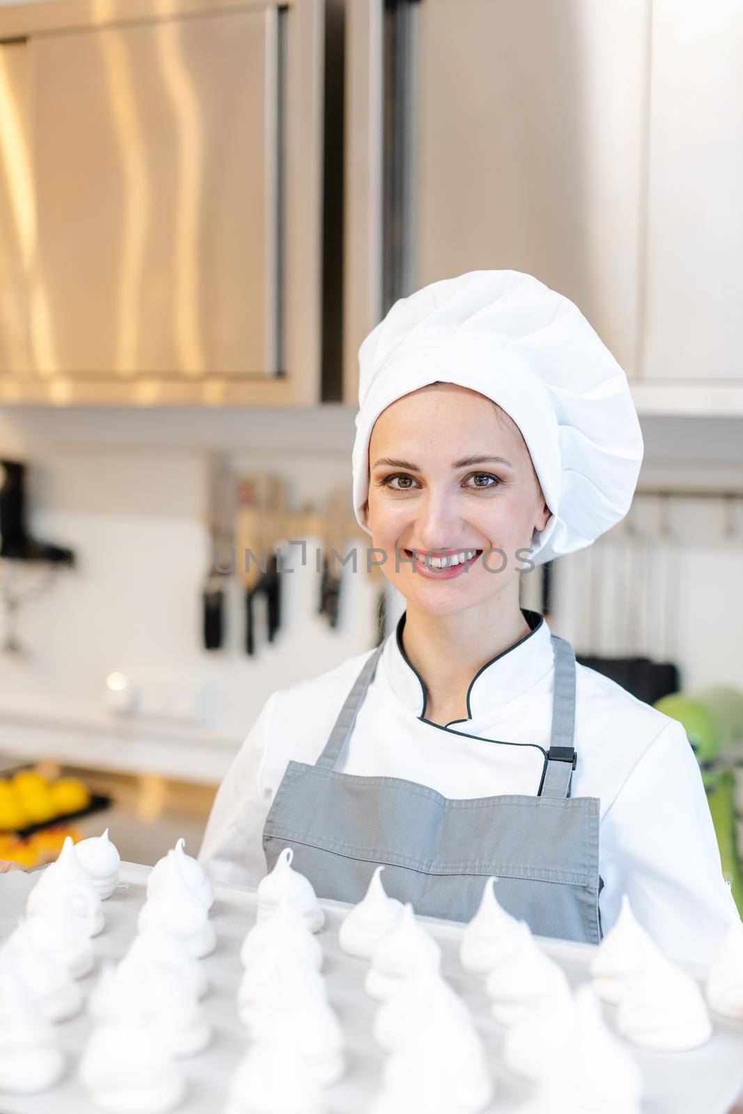 Patissier working in her bakery shop with lots of meringue