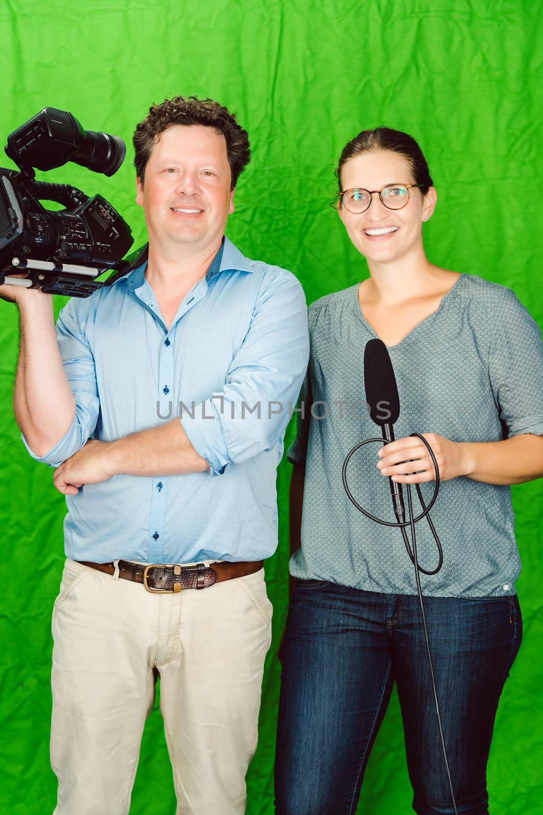 Crew of reporter and cameraman posing in the studio looking into the camera