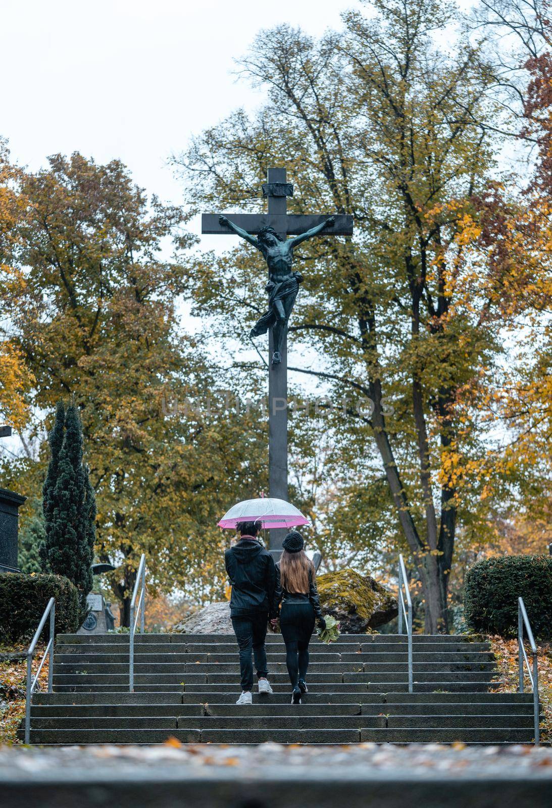 Man and woman walking up steps on cemetery towards a cross by Kzenon