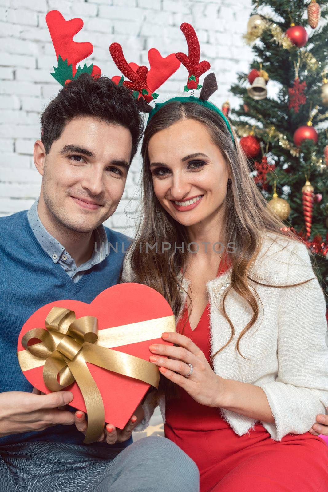 Woman and man in love with presents for Christmas in front of decorated tree