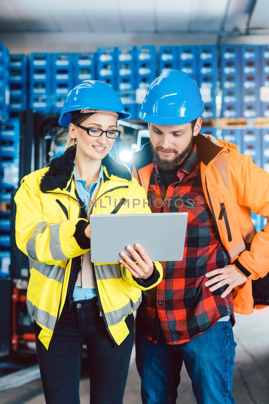 Woman and man as workers in logistics center using computer checking data