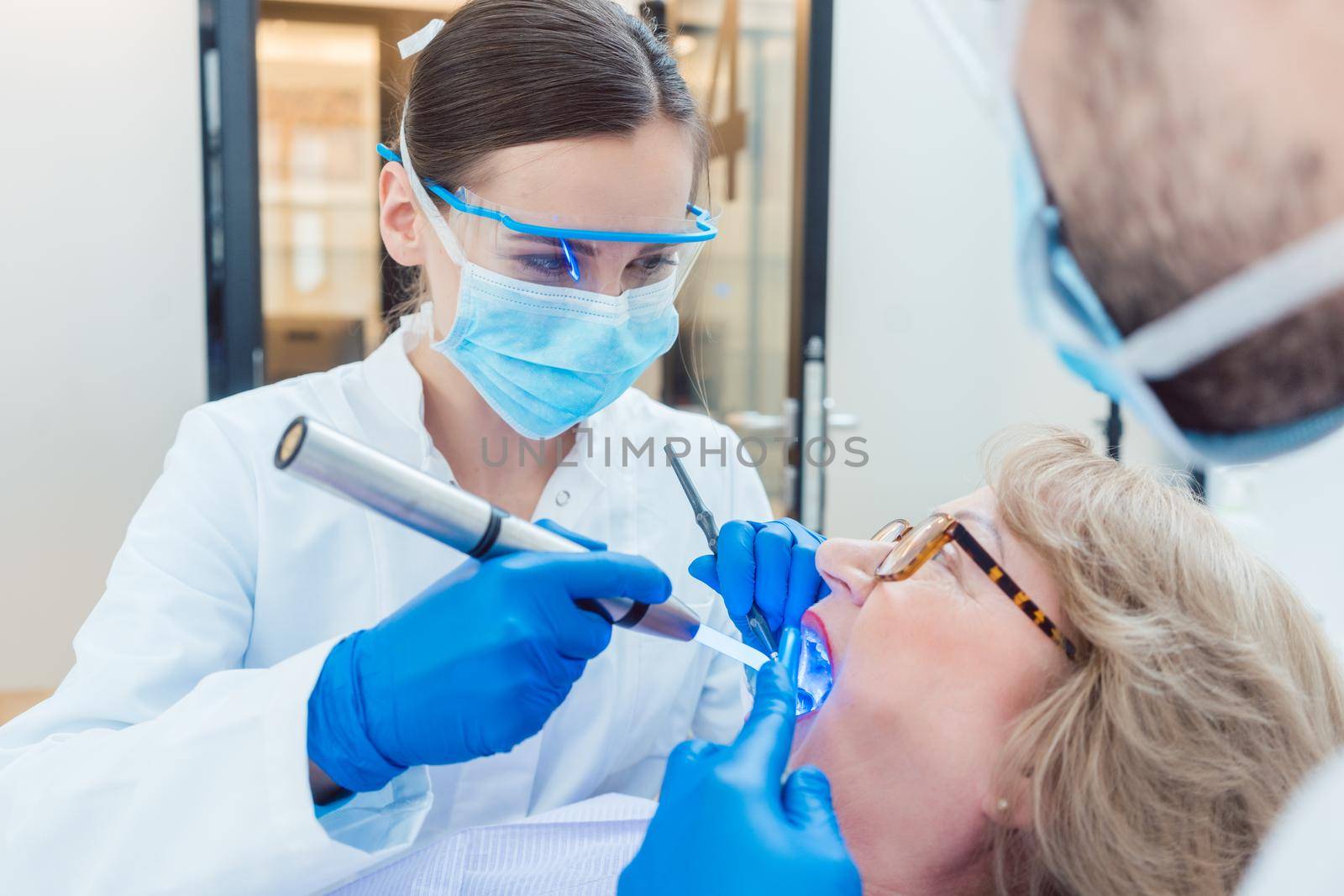 Dentist during treatment of senior patient woman looking into mouth