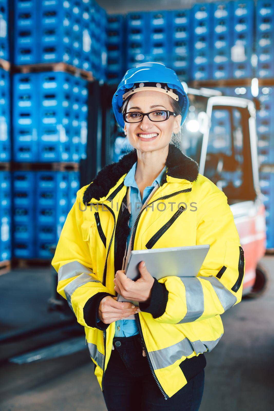 Worker woman in a logistics company with a tablet computer standing in the warehouse