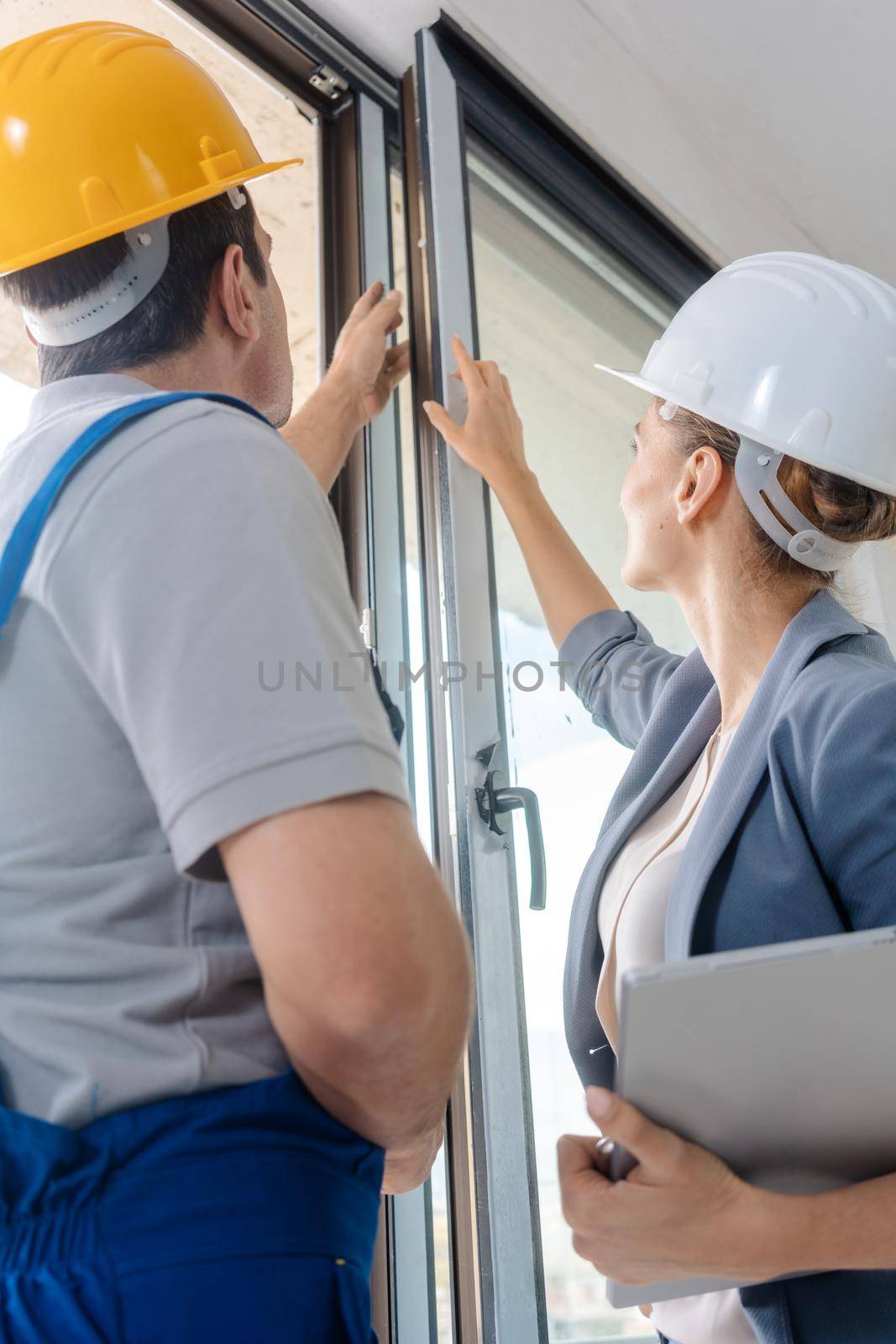 Architect woman and construction worker checking windows on site