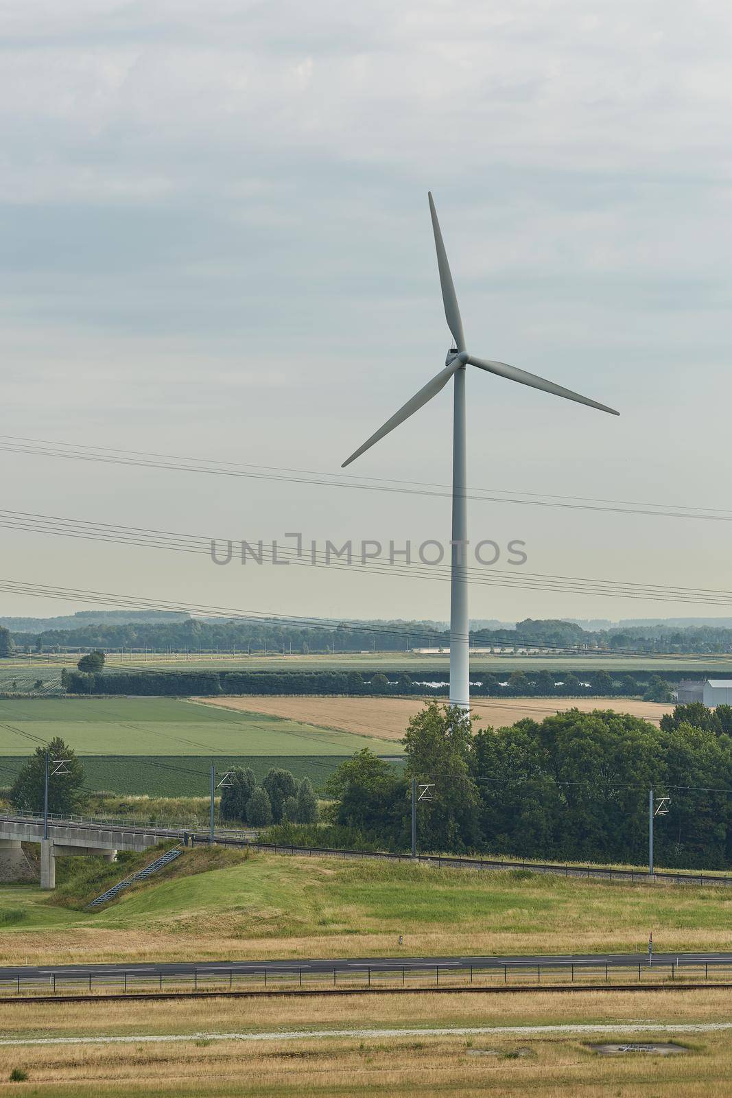 Windmills as wind turbine power generators placed within the countryside of green country of Netherlands.
