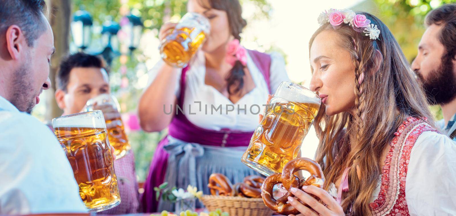 Woman in Tracht looking into camera while drinking a mass of beer by Kzenon