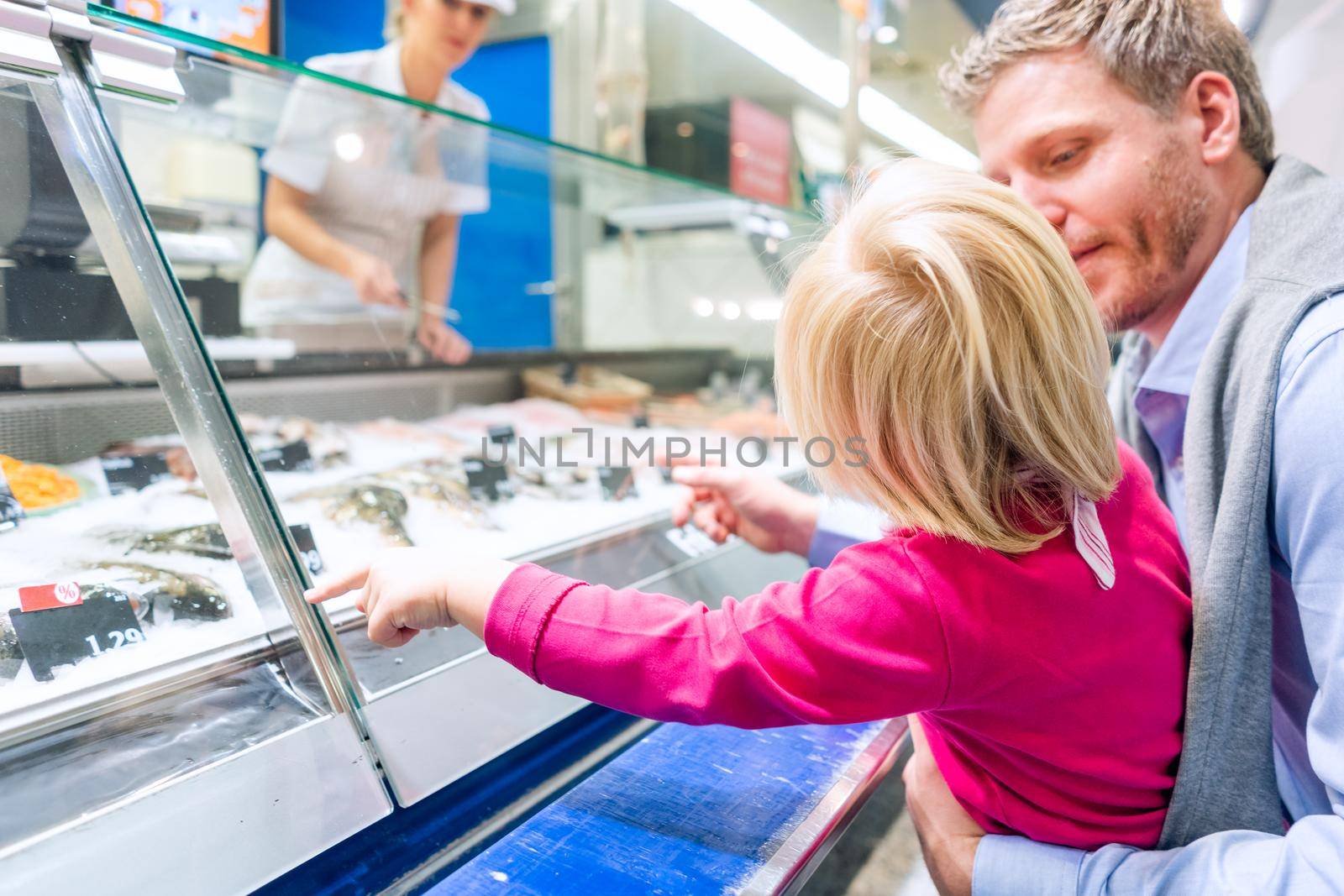 Family at the fish counter in a supermarket looking at what is on offer