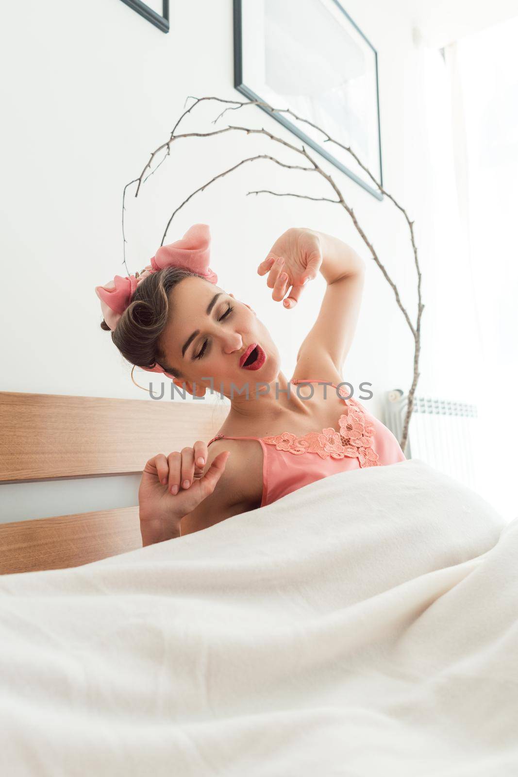 Sensual woman waking up in the morning stretching in bed still being tired