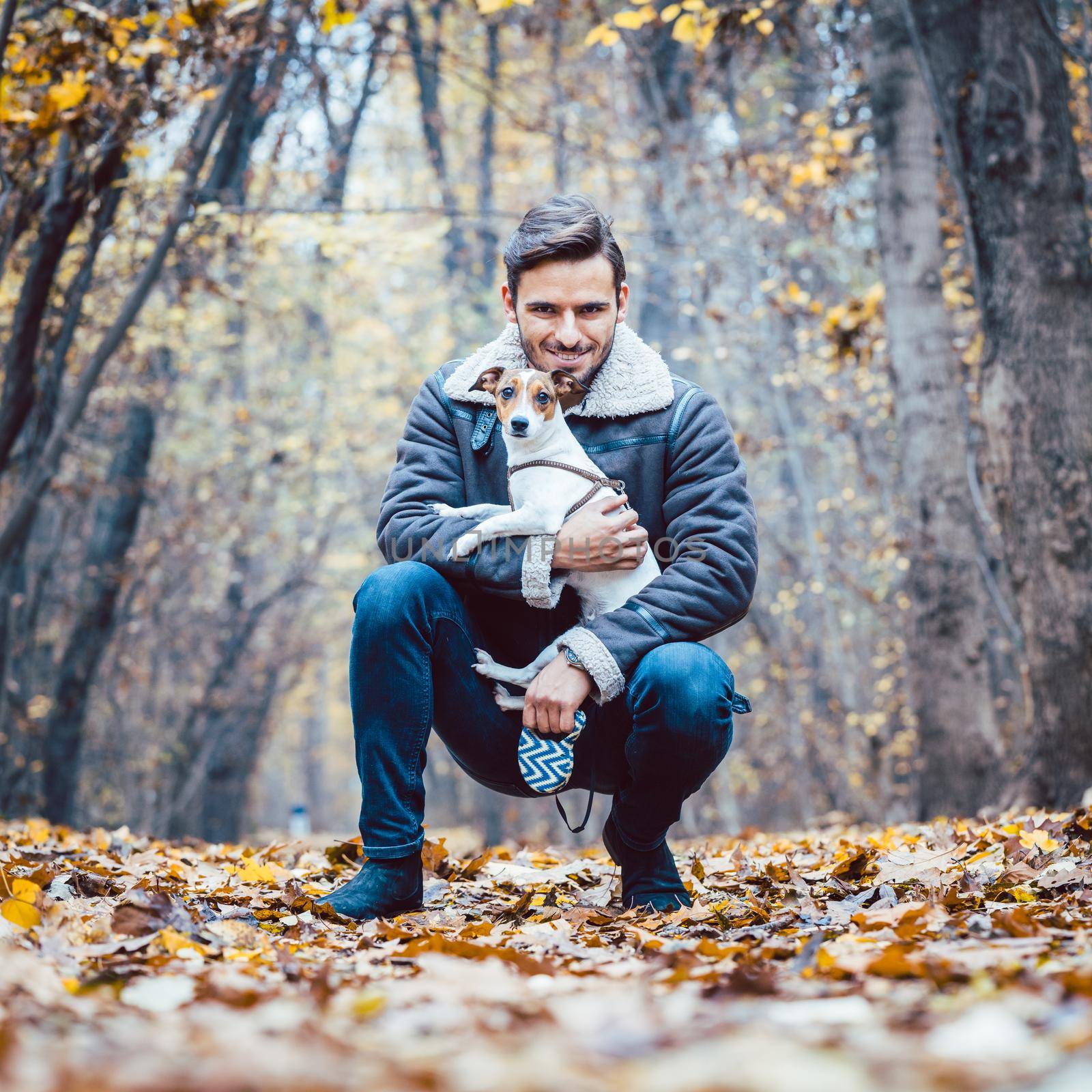 Young man walking his dog having a stroll in the autumn park by Kzenon