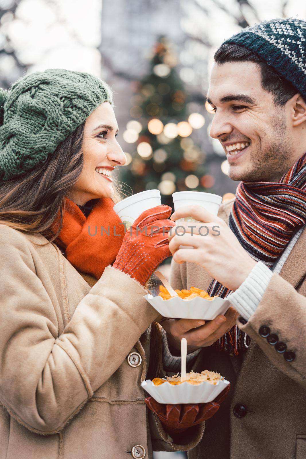 Couple with food and drink on Christmas market looking at each other