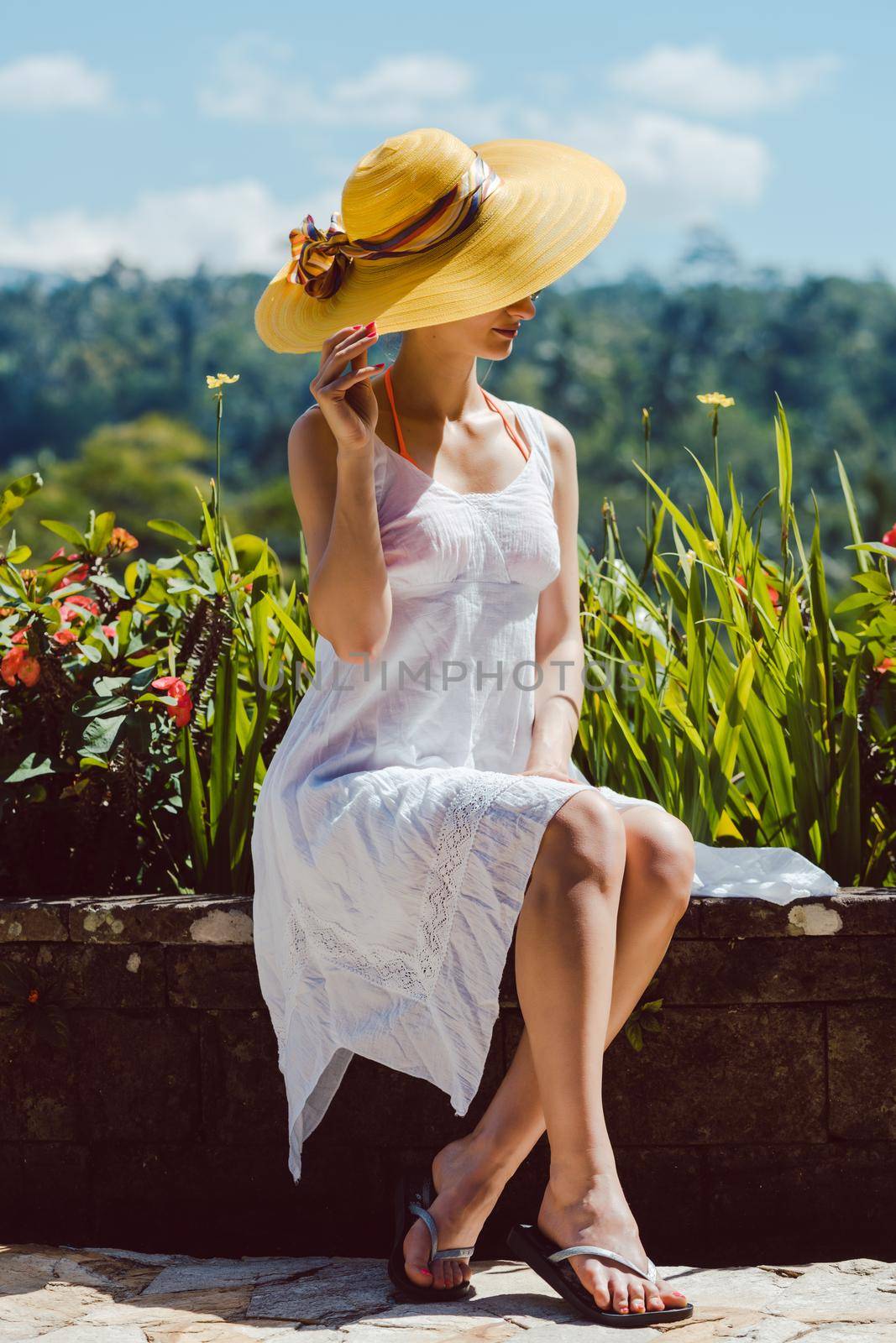 Woman sitting in tropical garden enjoying the sun amid the lush green