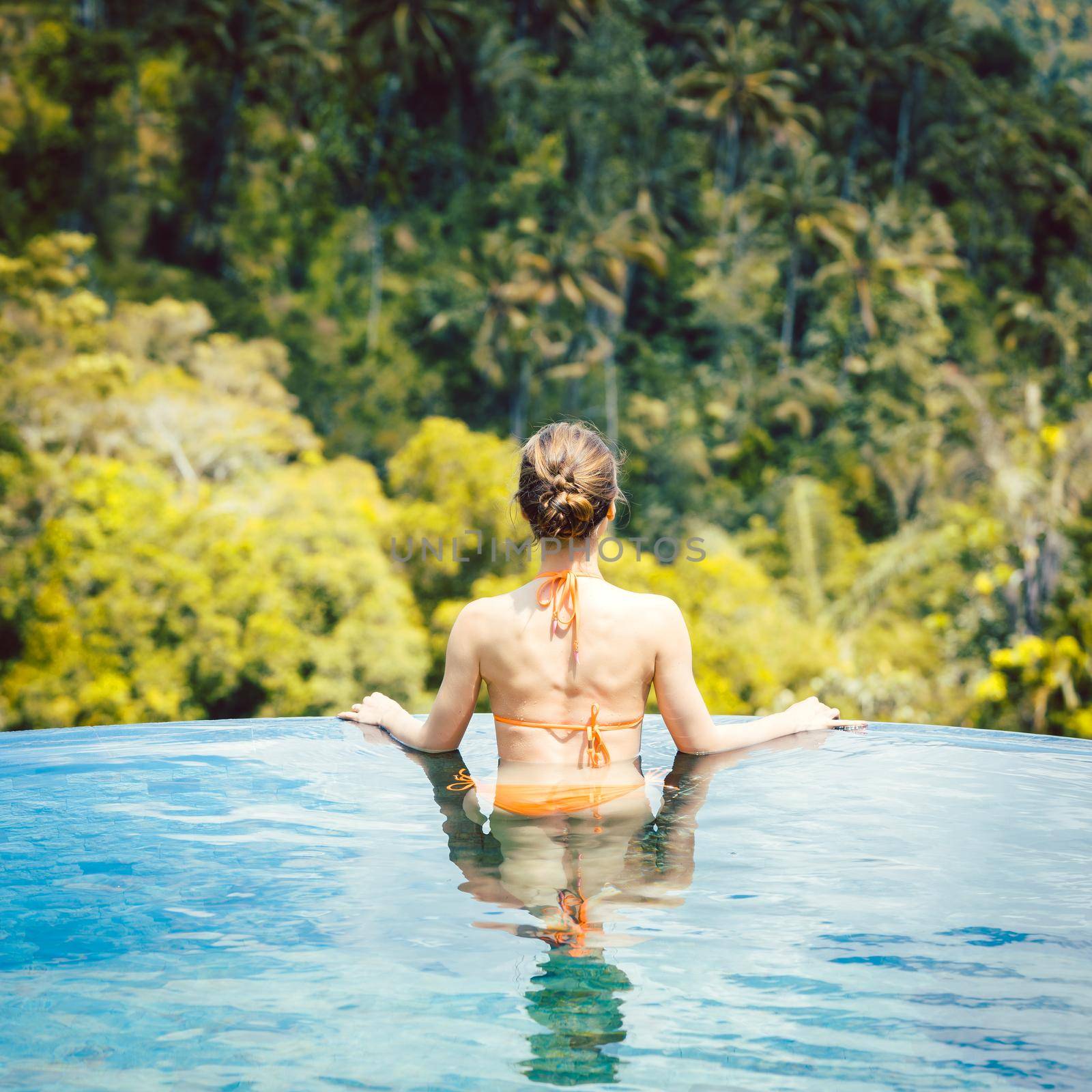 Woman in tropical vacation enjoying the jungle from the pool looking at the scenery