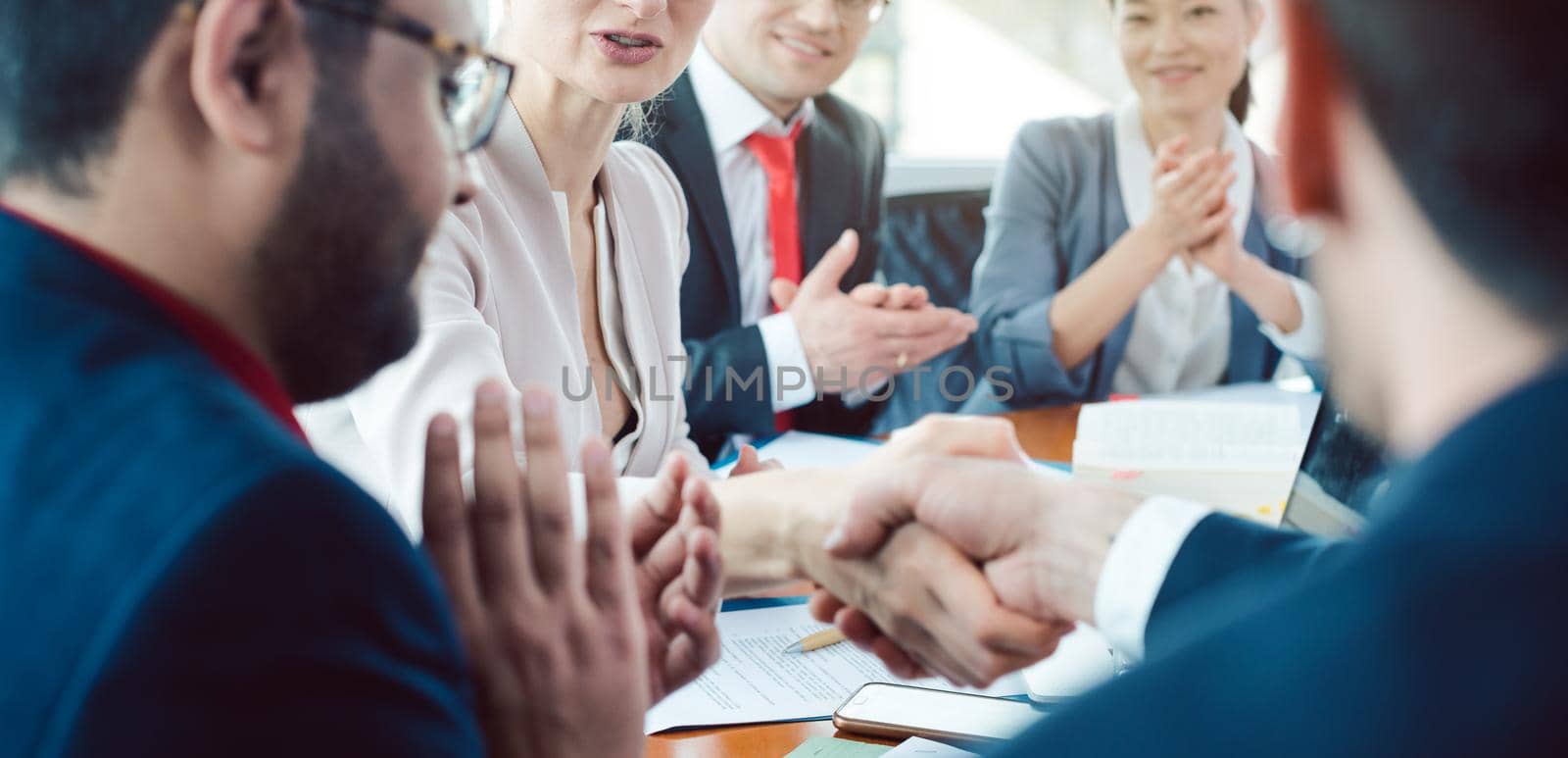 Team of business people negotiating an agreement closing the deal with handshake