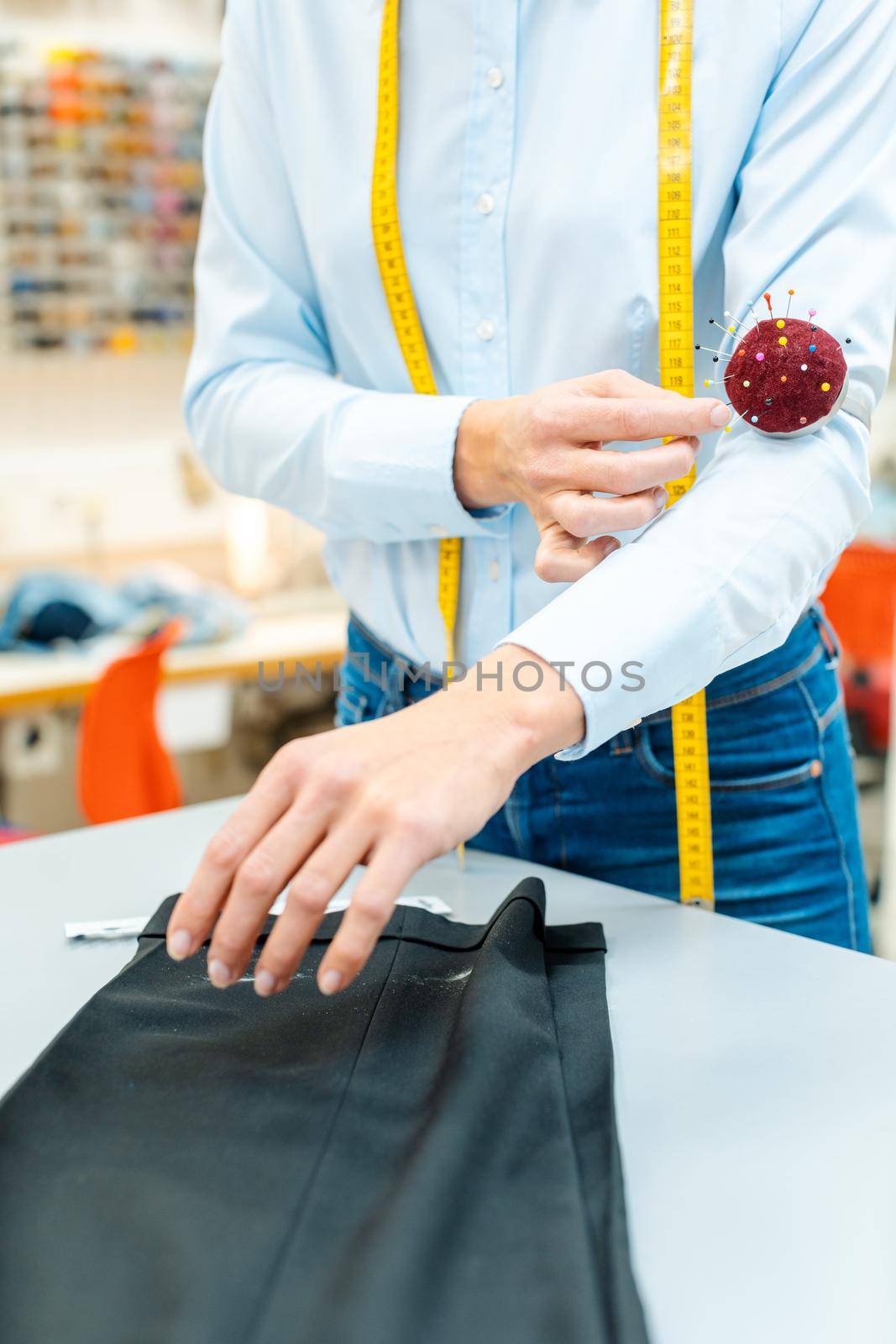 Alterations tailor working on some trousers using needles