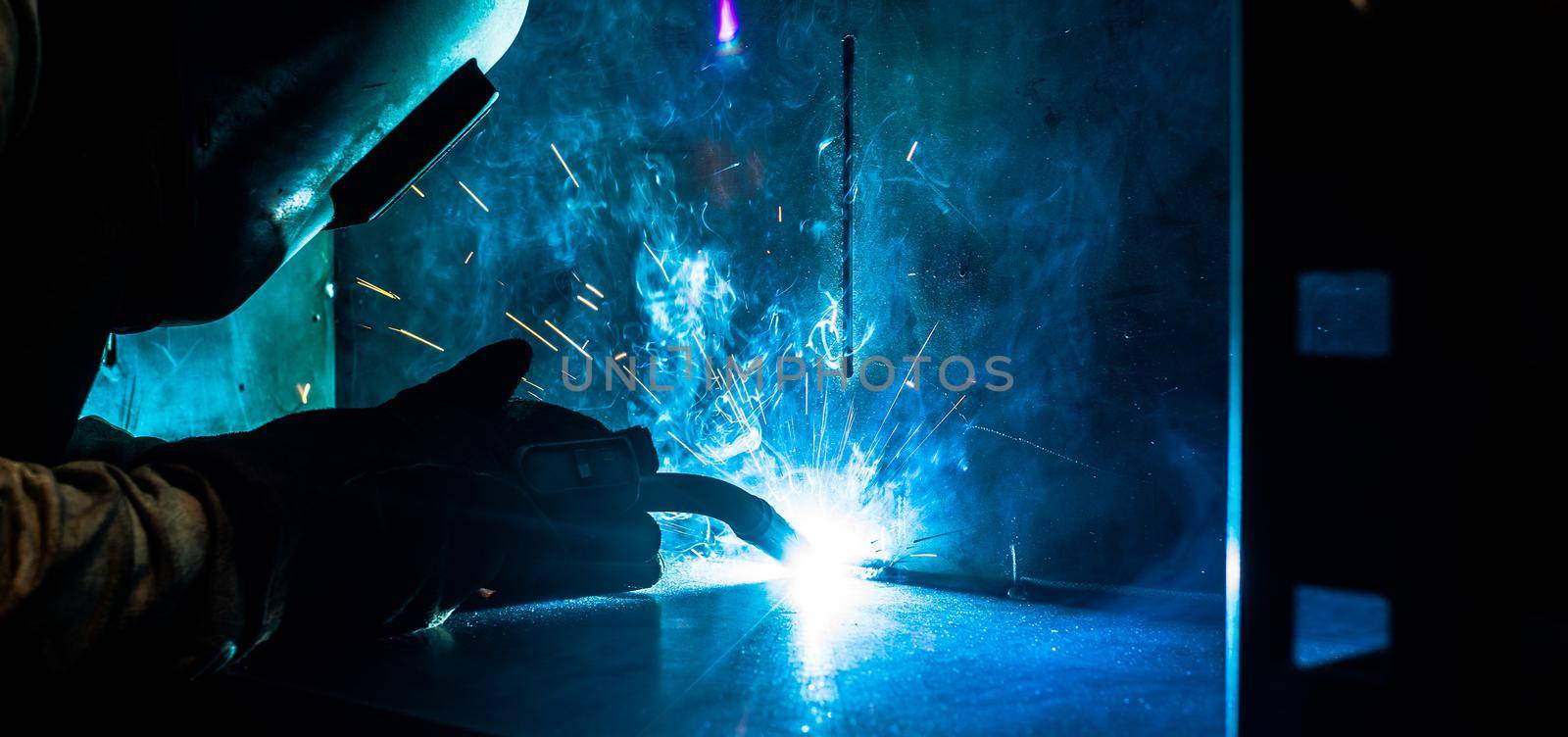 Welder working in factory with lots of sparks flying