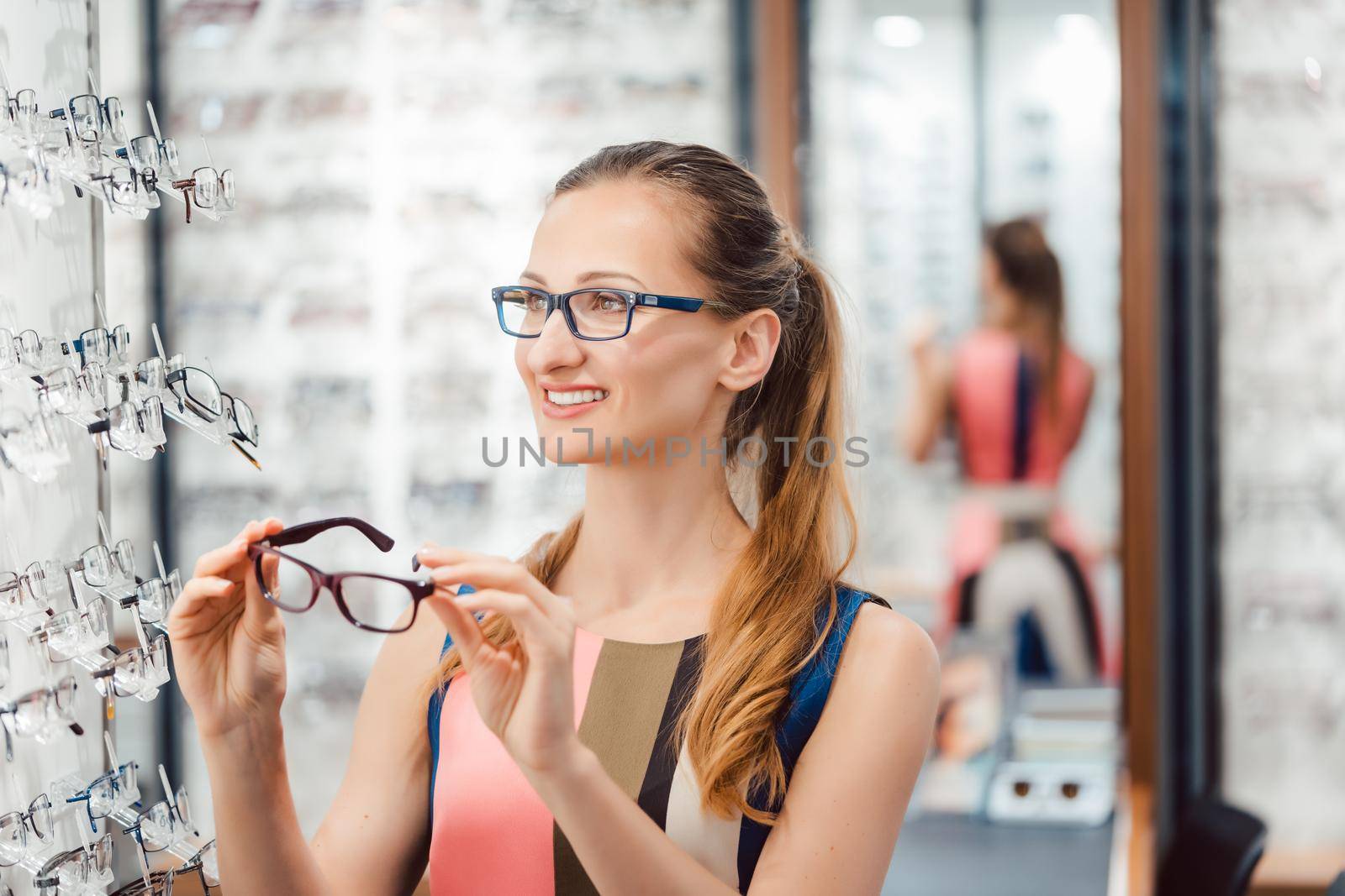 Beautiful woman choosing new glasses in store by Kzenon