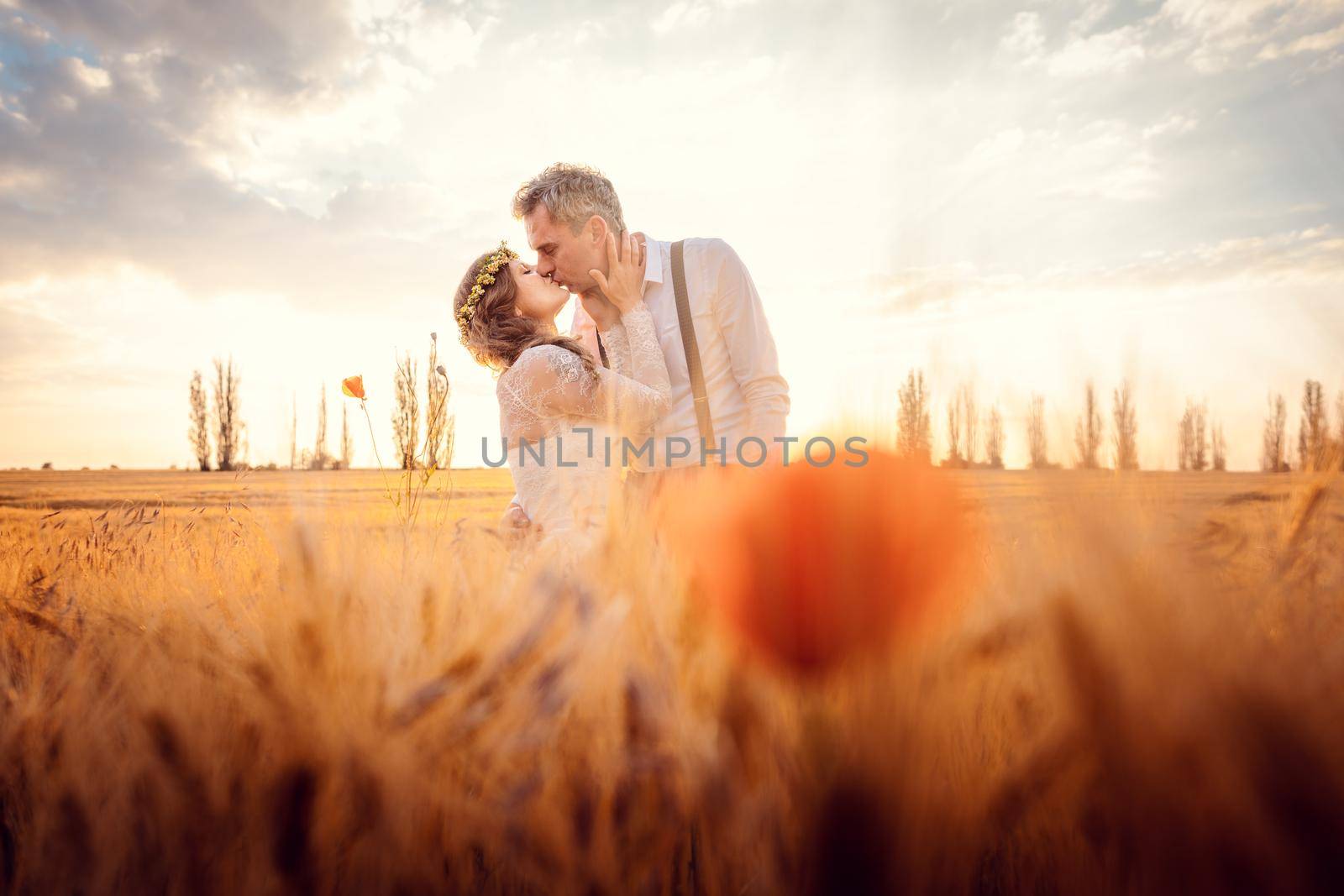 Wedding couple kissing in romantic setting on a wheat field by Kzenon