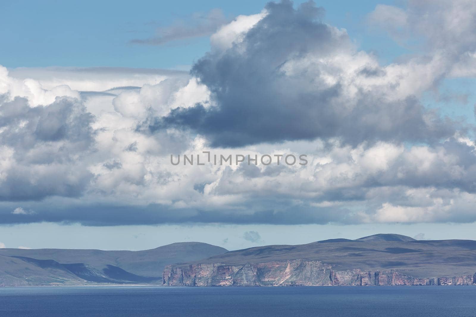 Orney cliffs with dramatic sky seen from John o'Groats over Atlantic ocean